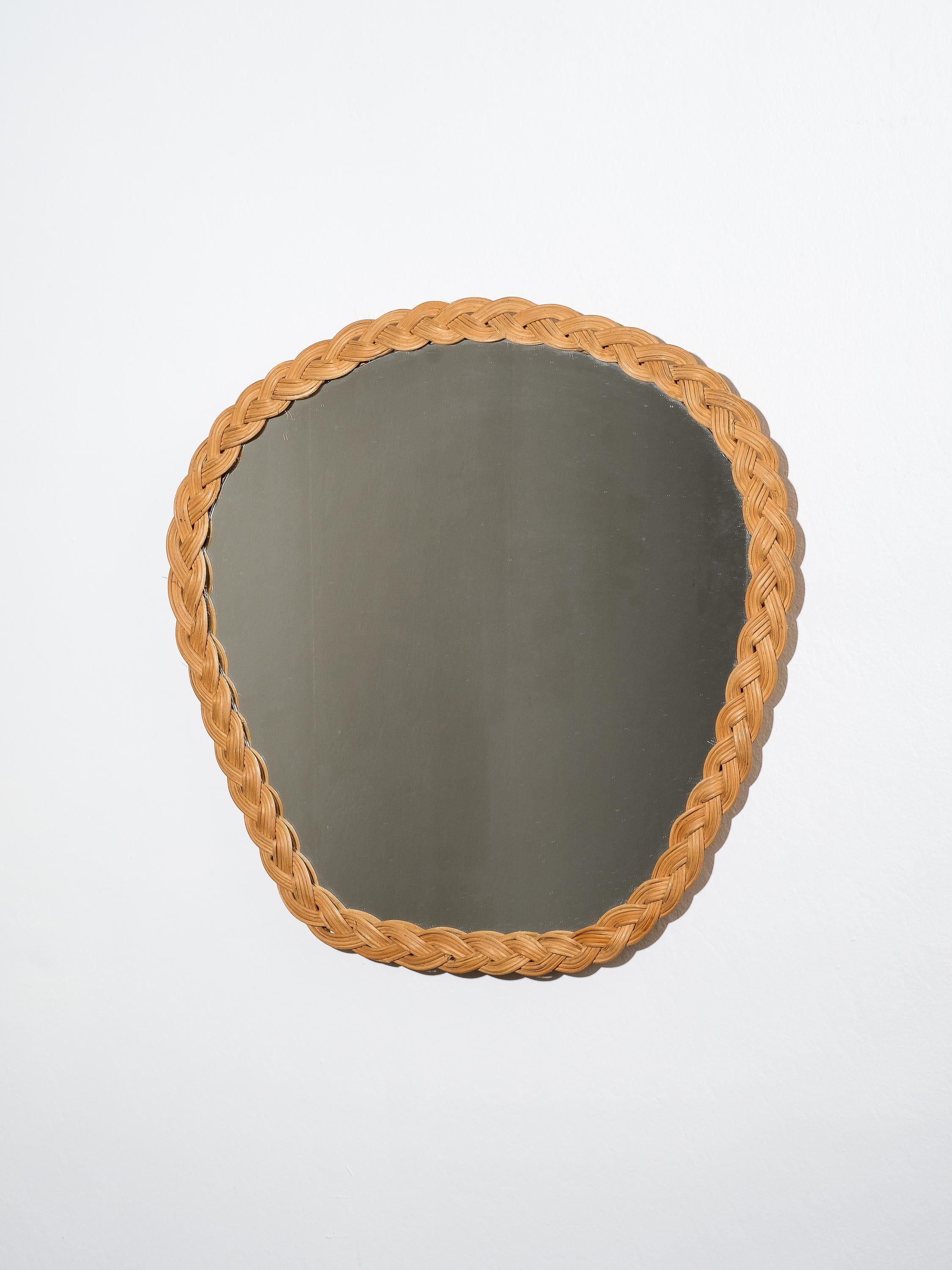 Un bellissimo specchio con cornice in rattan intrecciato a mano. Questo specchio presenta una lavorazione artigianale a treccia sulla cornice che lo rende altamente decorativo, Finlandia, anni '60. La treccia di rattan è larga circa 3 centimetri.
