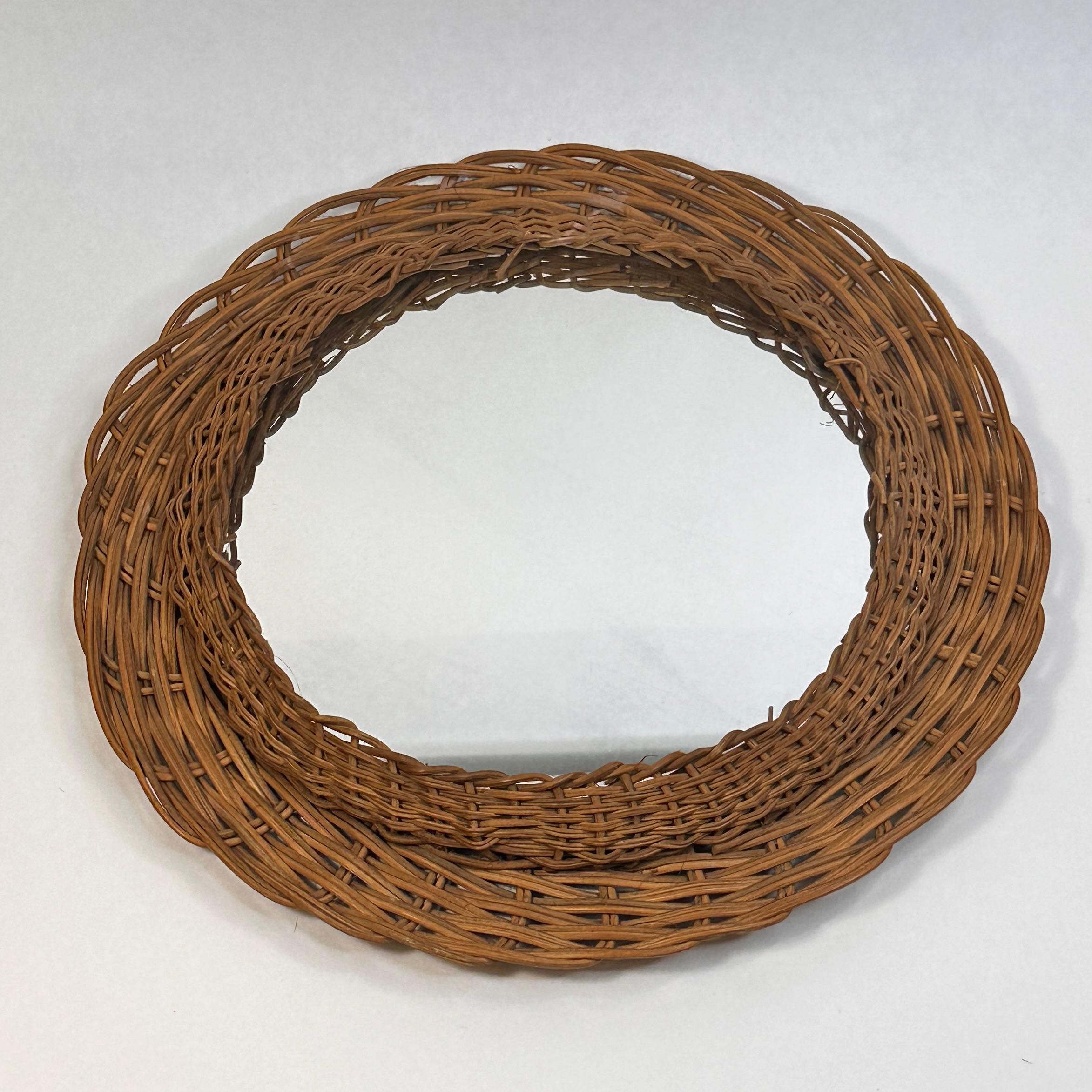 A beautiful handwoven round shaped rattan and wicker mirror. This mirror has a handcrafted braided work at the frame that makes it highly decorative, Germany, 1960s. Mirror viewable size itself is approximate 12 1/4