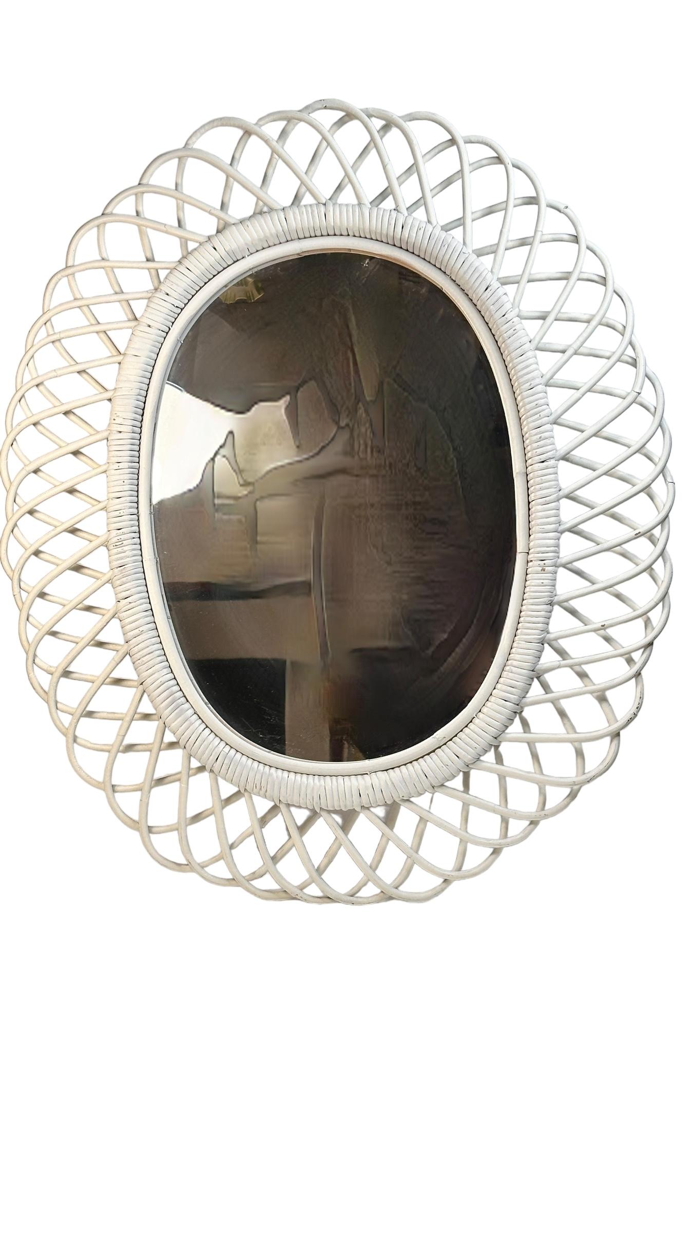 A flower burst or sunburst oval mirror handcrafted with rattan cane and wicker. A natural and fresh accent for any space with a taste of the Mediterranean Coast. These mirrors were typical in Italy in the 1960s-1970s. This would be a gorgeous piece