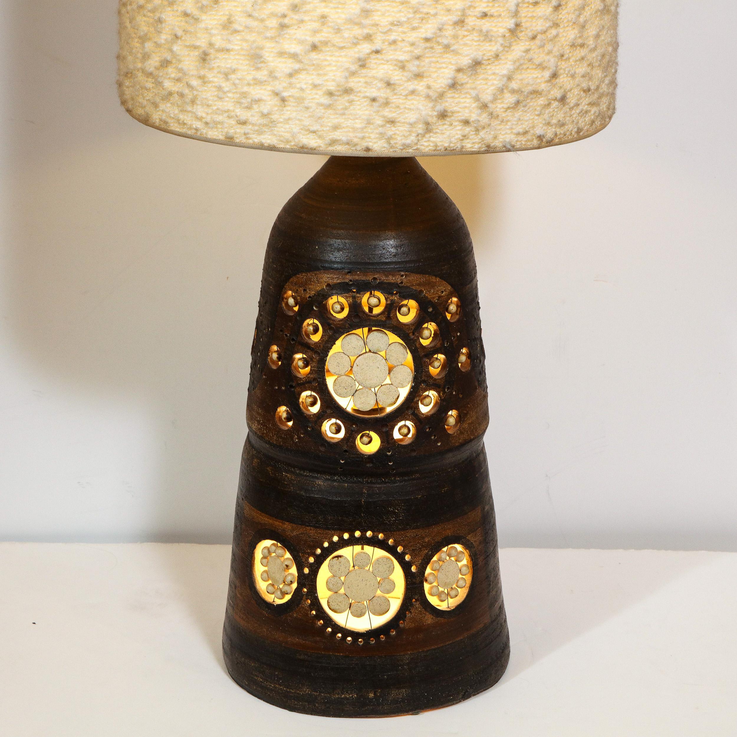 This sophisticated Mid-Century Modern table lamp was realized by the acclaimed designed Georges Pelletier in France, circa 1950. It features a conical ceramic body hand painted in a rich espresso hue with chestnut accents throughout and circular cut