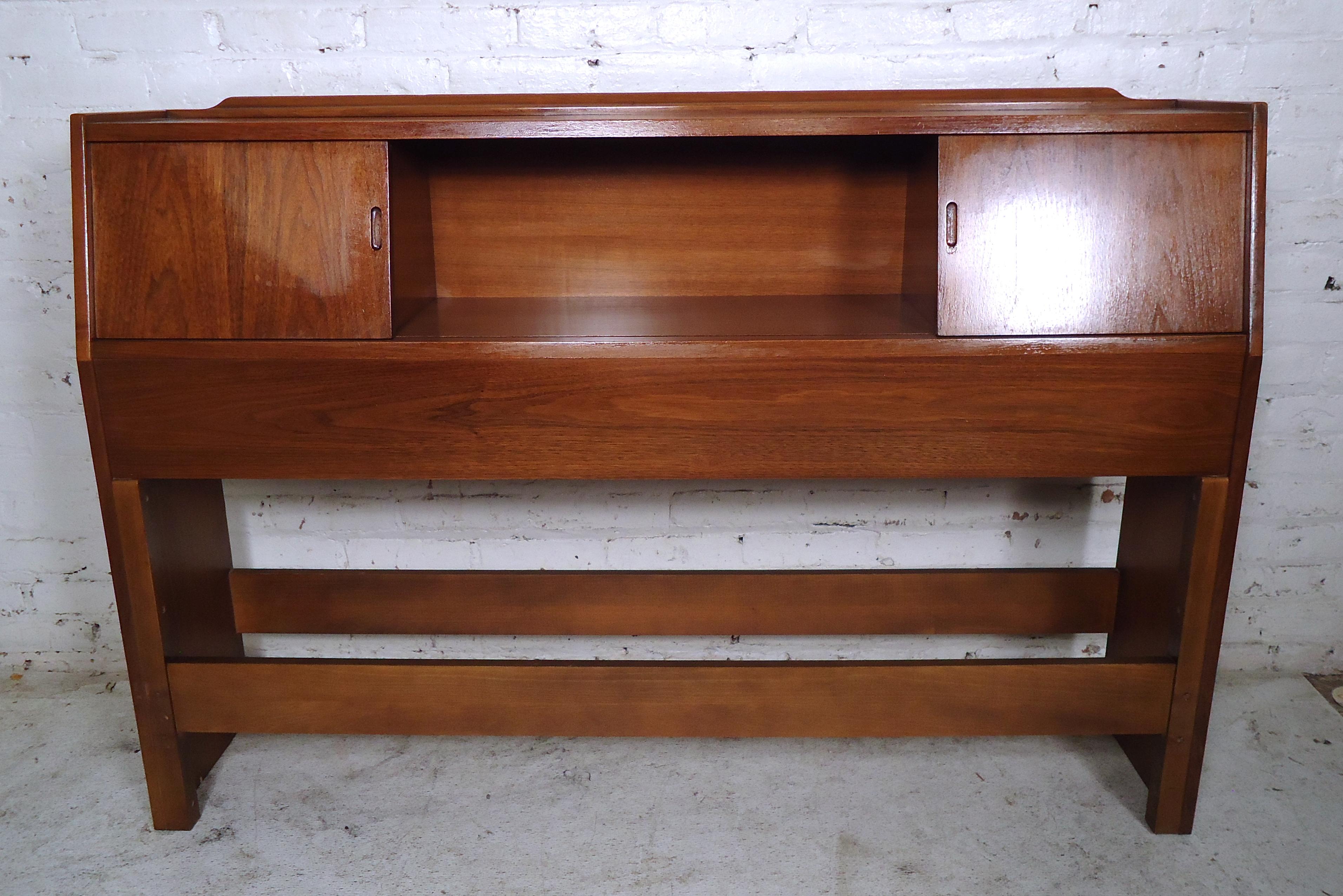 Vintage modern headboard featured in rich walnut grain, two sliding doors with storage space, and a middle storage compartment. 
(Please confirm item location - NY or NJ - with dealer).