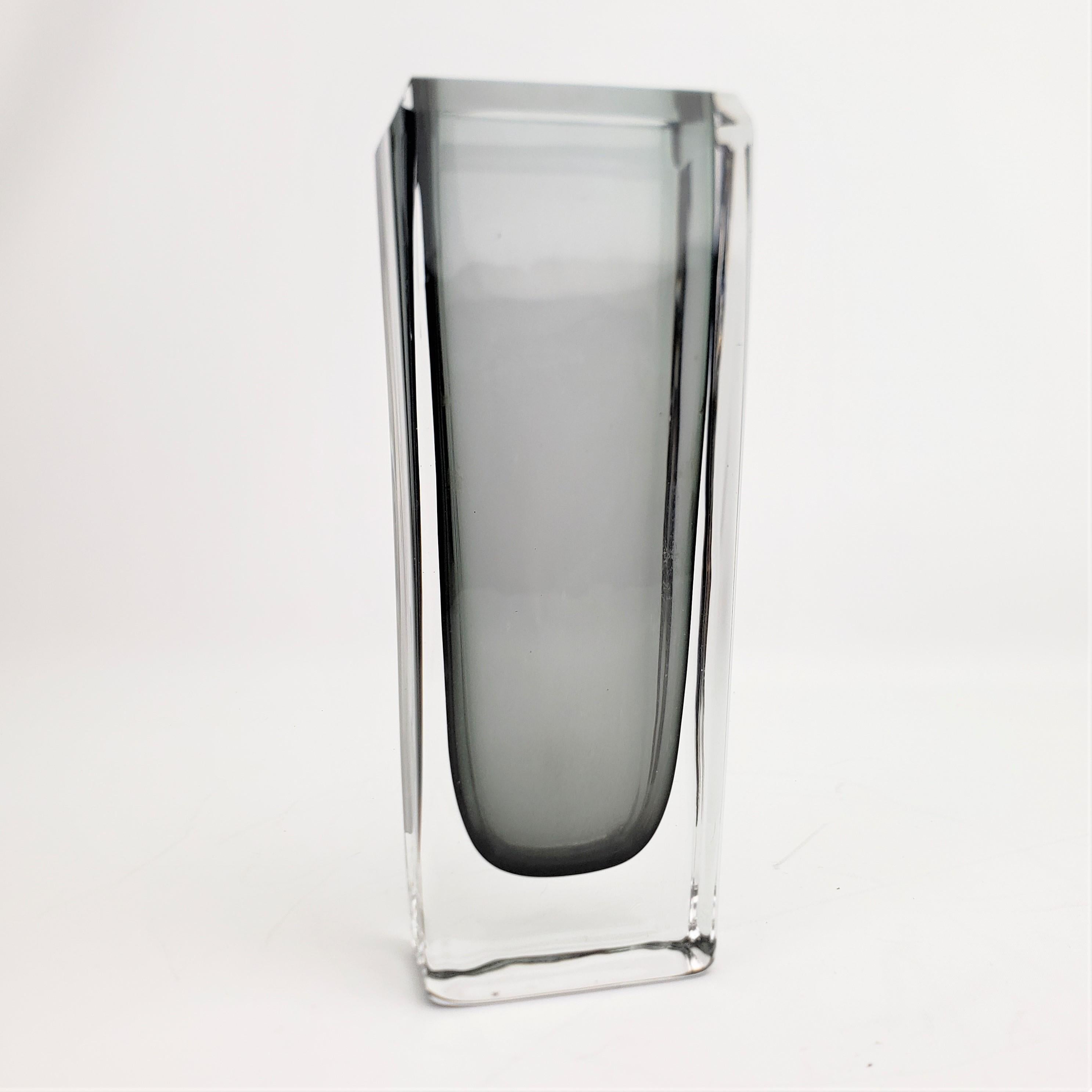 This very thick and heavy grey and clear art glass vase is signed by an unknown artist, but presumed to originate from Scandinavia, likely Sweden, in approximately 1970 in the period Mid-Century Modern style. The vase is done in a thick clear glass