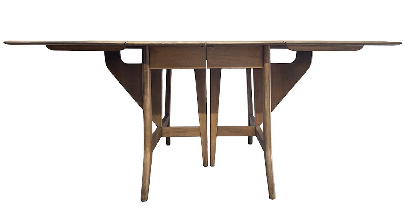 This lovely and classic Heyward-Wakefield dining table is in a light taupe finish. Tables length when the drop leaves are down is 26”. This is a great space saving piece! Original finish and in great shape. Chairs are listed in a separate