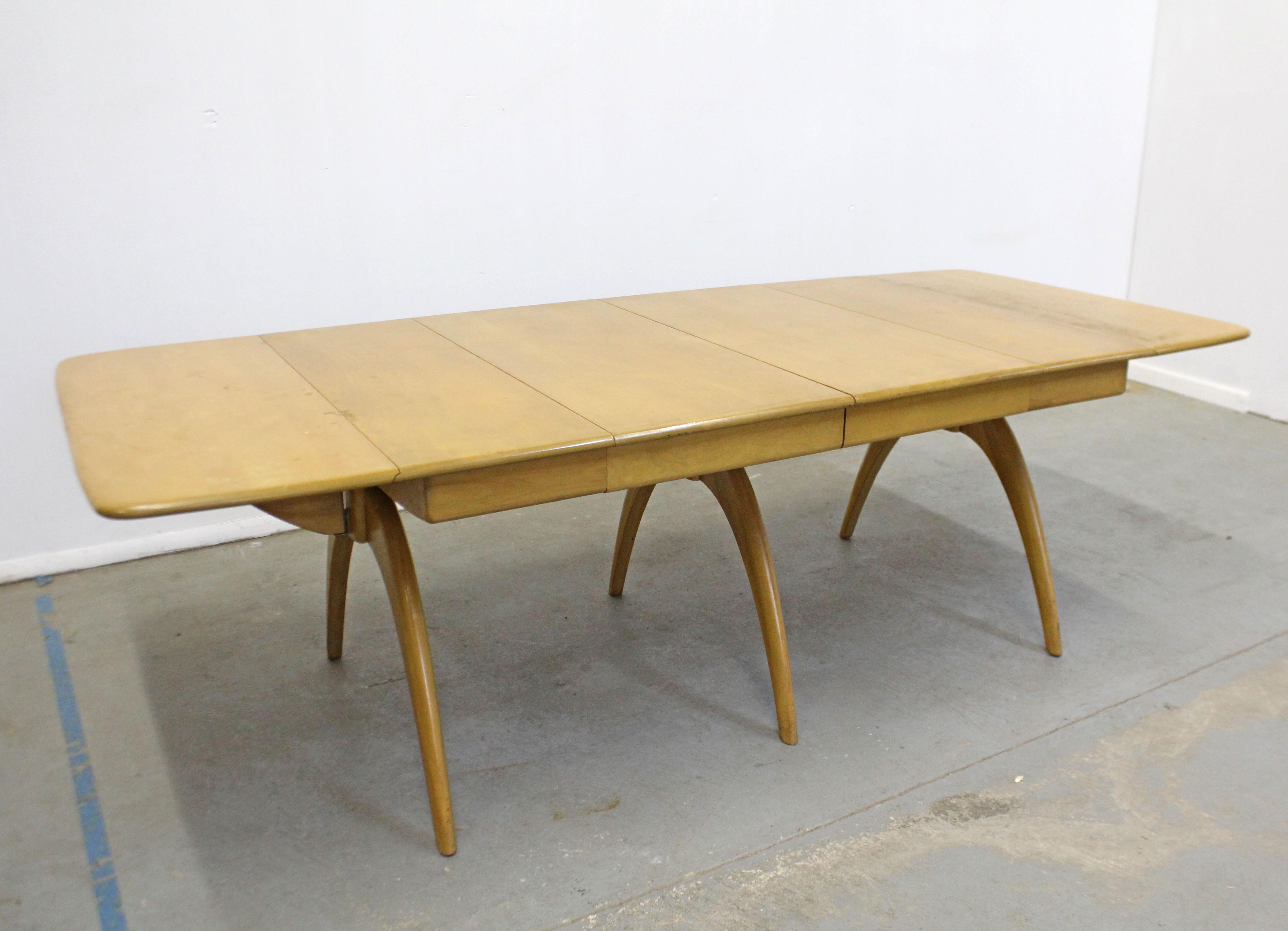 What a find. Offered is a Heywood Wakefield 'Butterfly' drop-leaf dining table with two extension leaves in a wheat finish. Even with its strong construction and sturdiness, this table features a particularly streamlined design and is ideal for