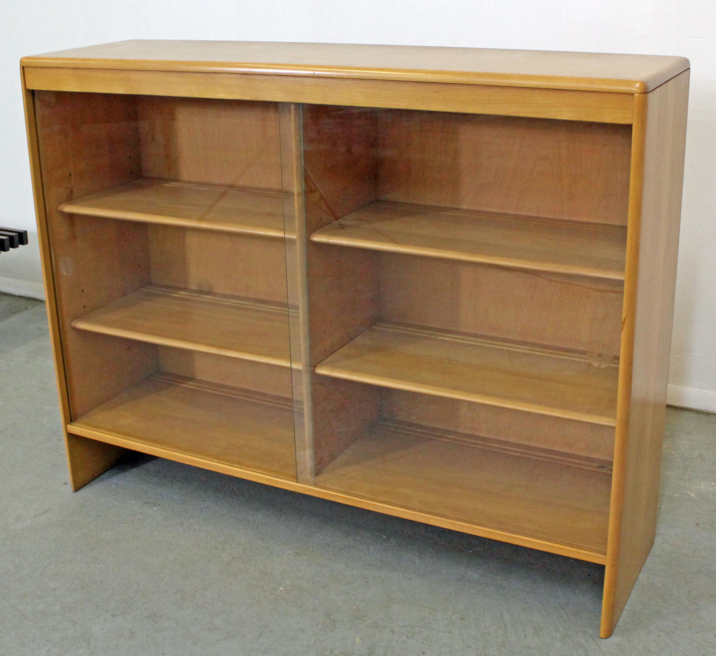 What a find. Offered is a Heywood Wakefield hutch top. It can be used as a bookcase or added to another piece. Features two sliding glass doors and adjustable shelving. It is made of birch with a 'Champagne' finish. It is in good condition for its