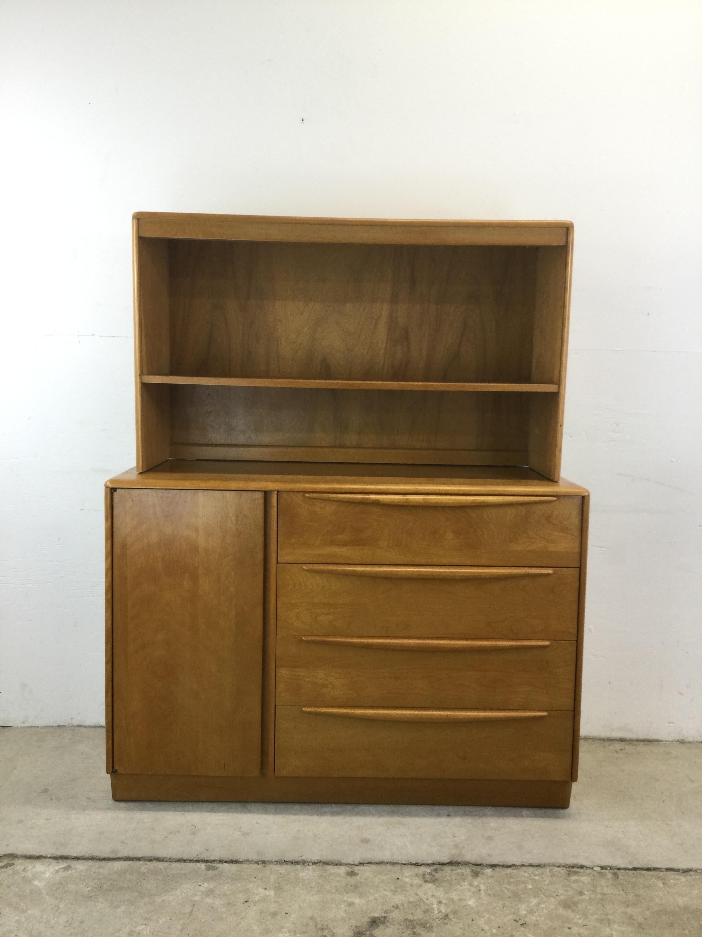This mid century modern china cabinet by Heywood Wakefield features hardwood construction, original Wheat finish, two piece construction with removable top cabinet.  Sliding glass doors and adjustable shelves in the upper cabinet.  Four drawers, one