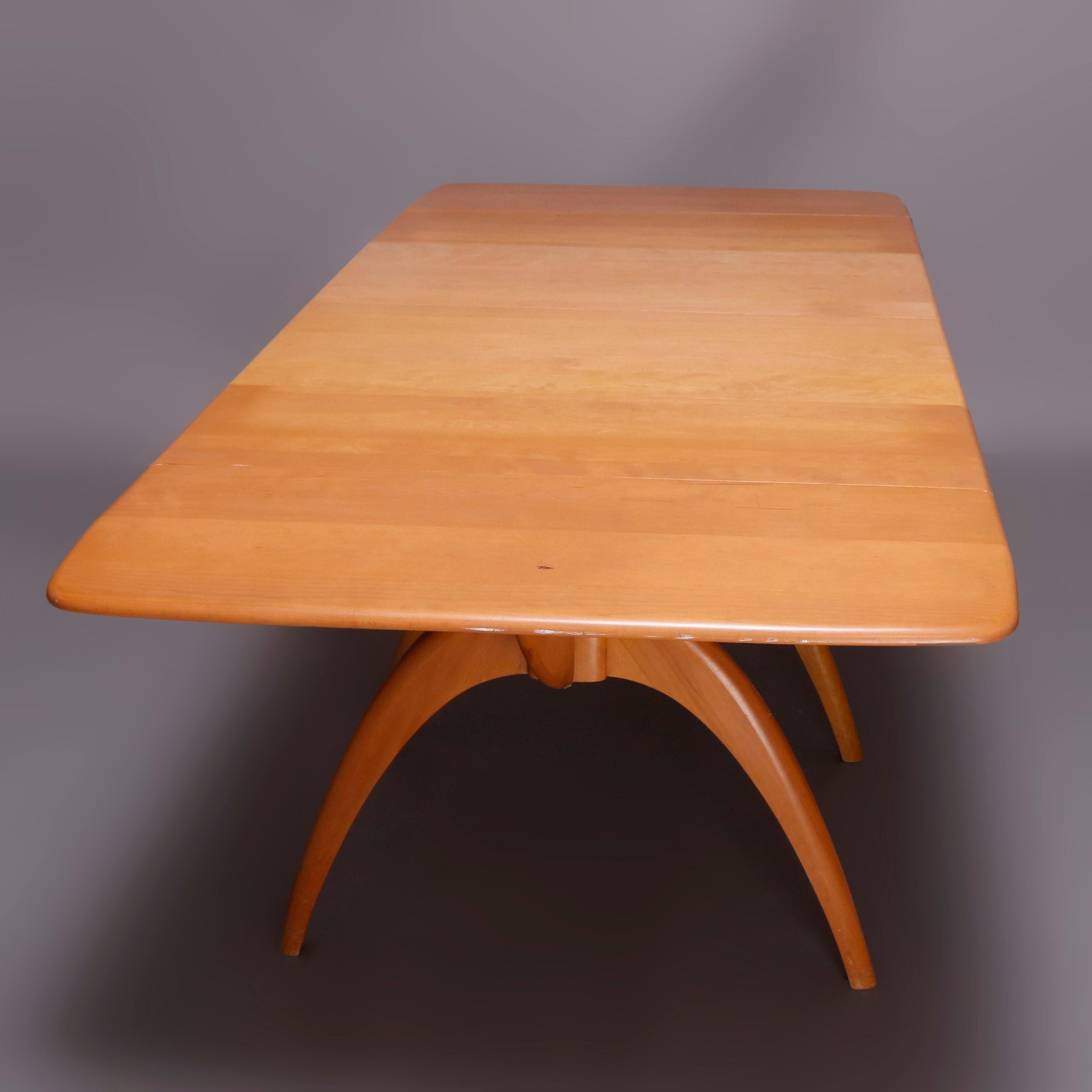 A Mid-Century Modern dining set by Heywood Wakefield offers birch construction with extension table in Wish Bone pattern having drop leaf top with two leaves surmounting convex legs, Champagne finish, maker mark as photographed, mid-20th