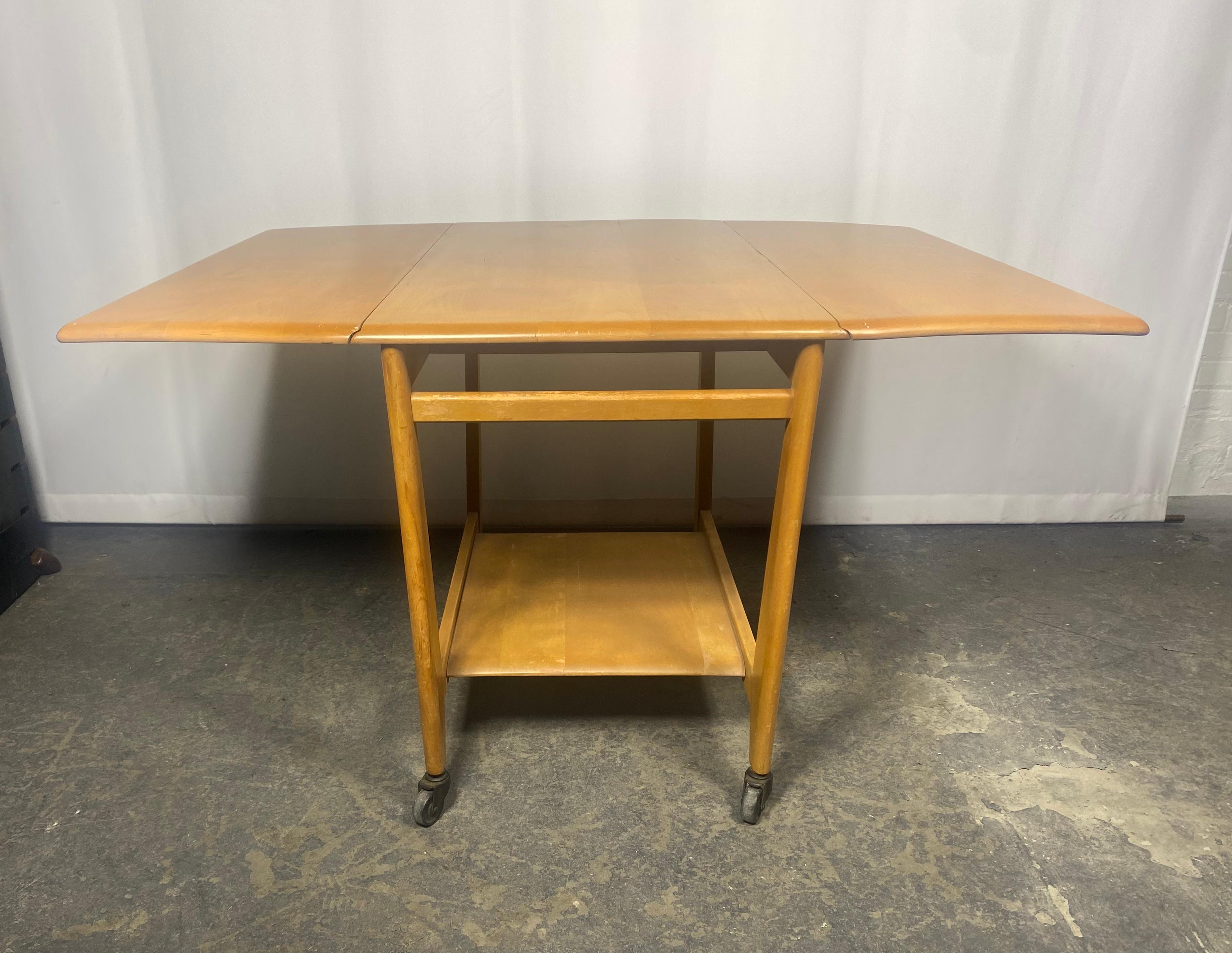 Rare Mid Century Modern Heywood Wakefield Drop Leaf Serving Bar Cart..Nice original condition.Wonderful color ,patina, design.

Multi-purpose serving cart for use as a bar cart, a serving cart for large dinners, a breakfast table for two, or an