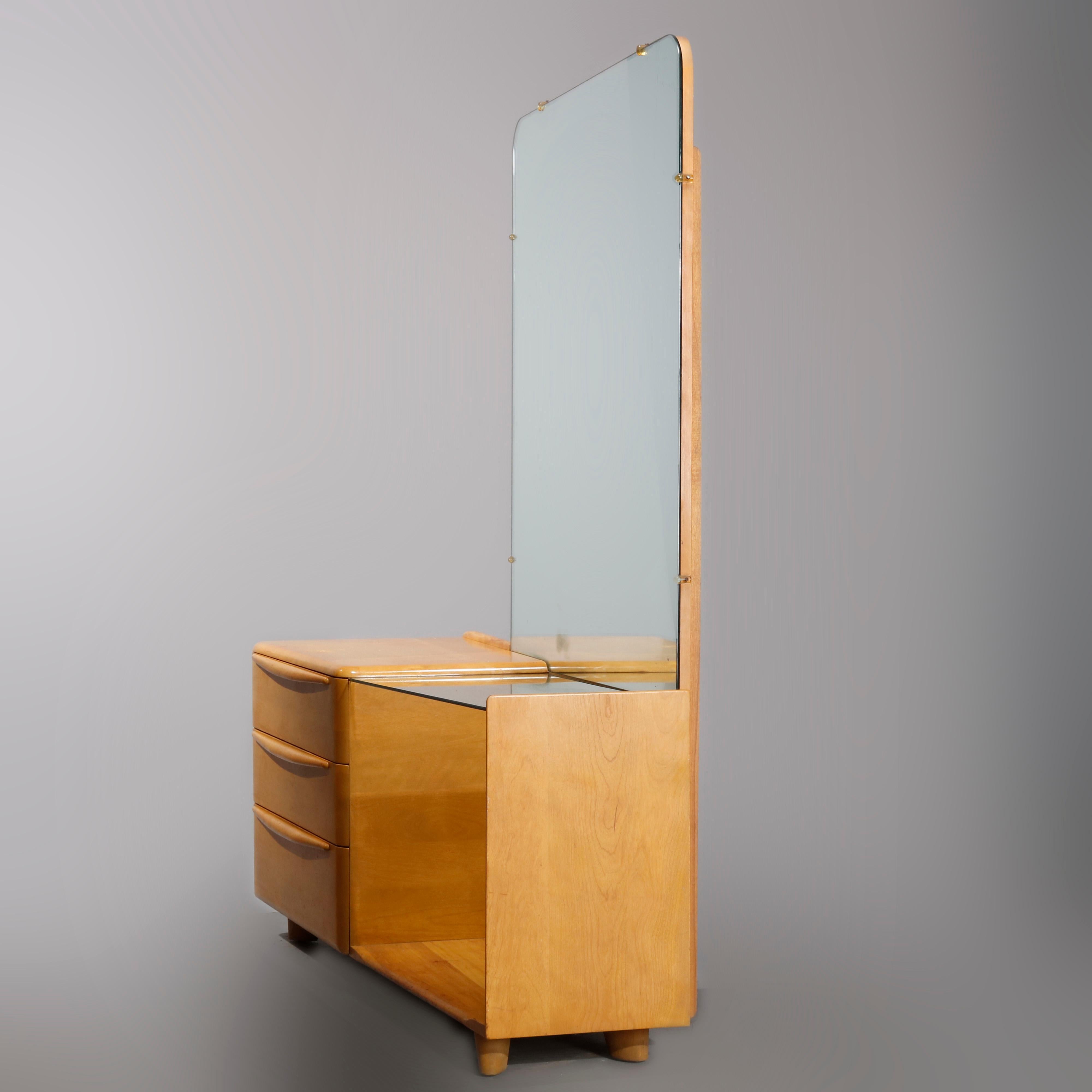 A Mid-Century Modern dressing table by Heywood Wakefield offers birch construction in Encore design with wheat finish offers left drawer tower with full length mirror and glass top dressing table on right, labeled in drawer as photographed,