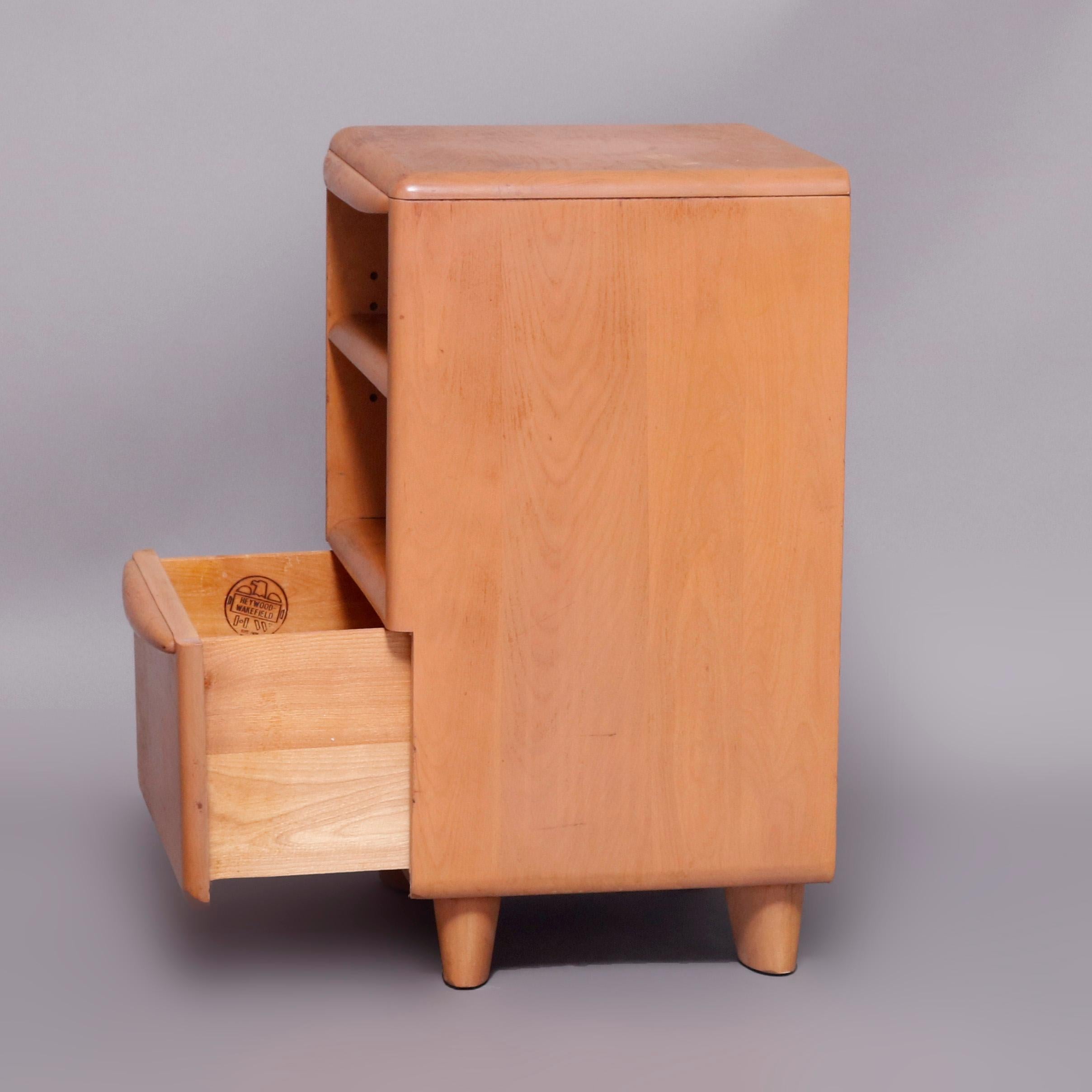A Mid-Century Modern night stand offers birch construction in the Encore pattern having Champagne finish with shelving surmounting lower drawer, 20th century

Measures: 25.25