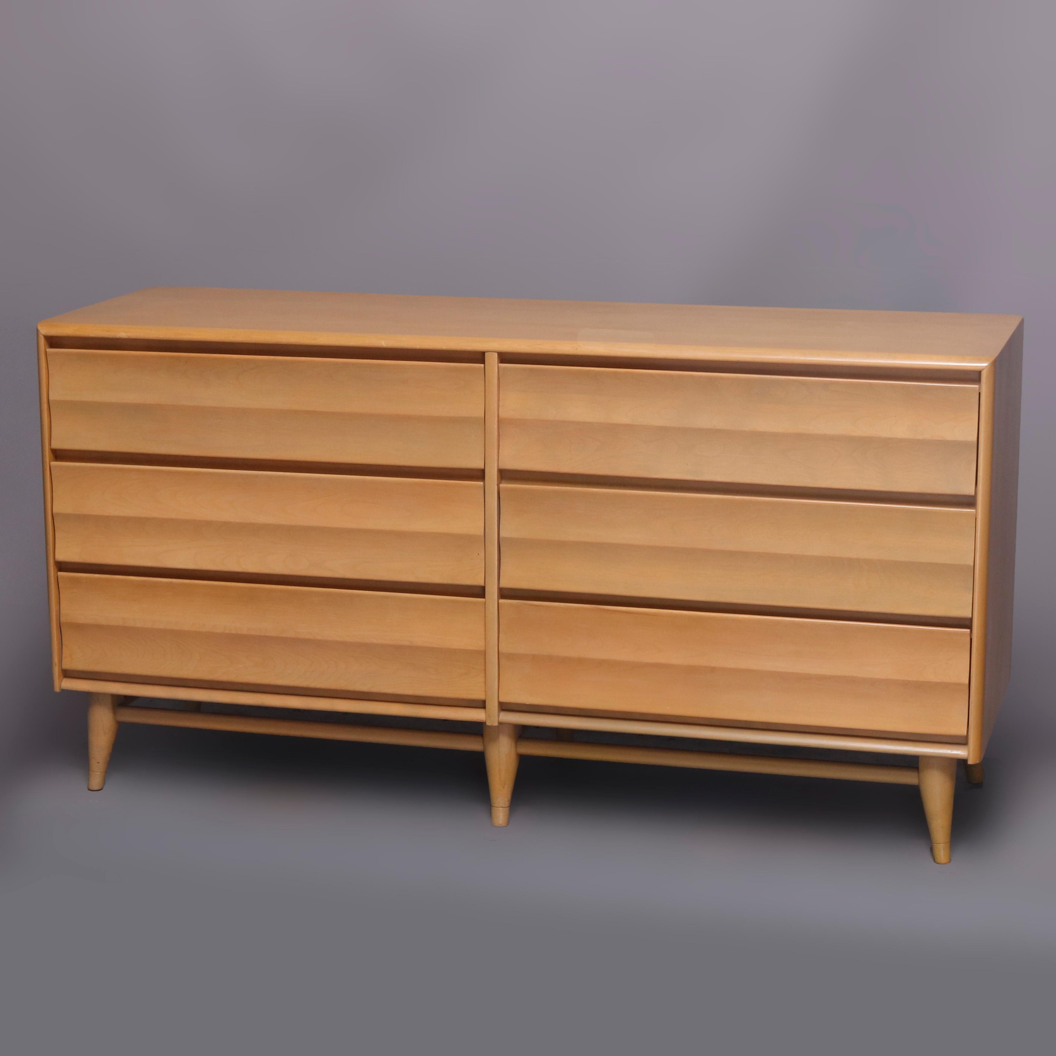 A Mid-Century Modern dresser by Heywood-Wakefield offers birch construction in harmonic pattern with 6-drawer lowboy and mirror in platinum finish, maker mark in drawer as photographed, mid-20th century

Measures: 66.75