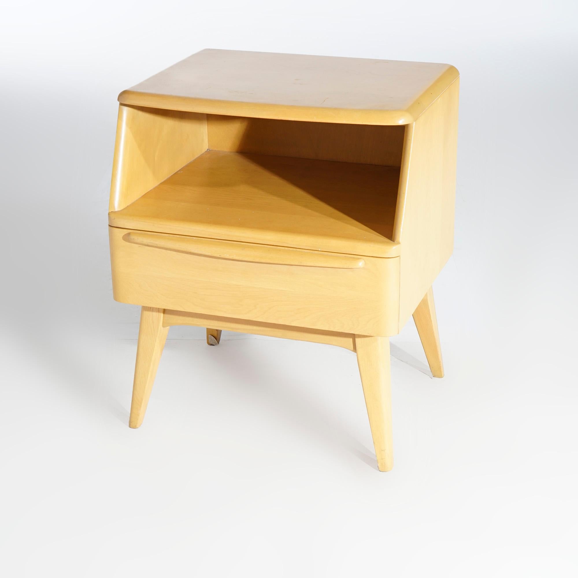 An Mid-Century Modern side stand by Heywood Wakefield offer birch construction with upper open shelf over lower drawer and raised on flared legs, finish in Wheat, maker label as photographed, c1950

Measures- 24.5'' H x 20'' W x 17'' D.