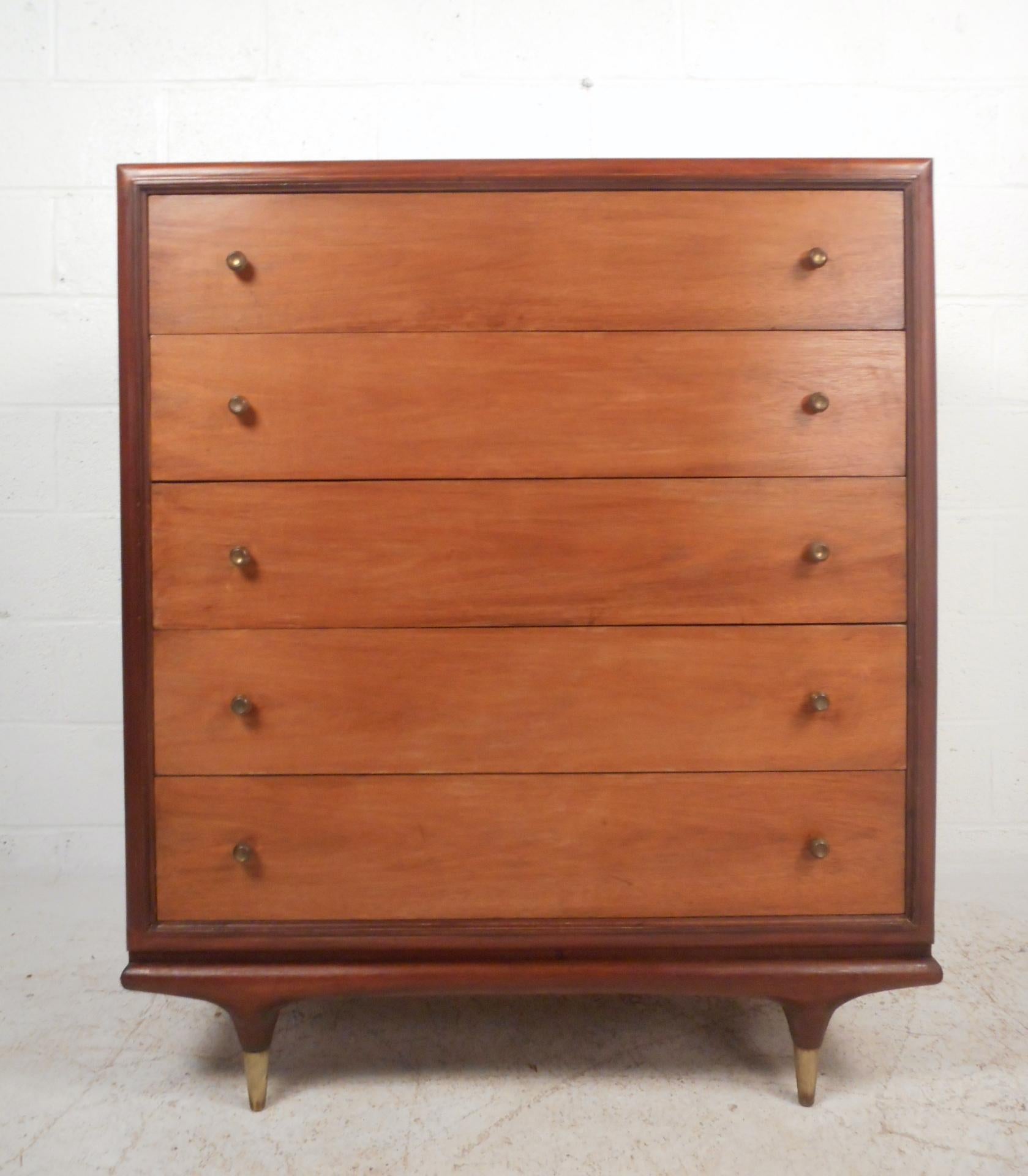 This gorgeous vintage modern highboy features a five large drawers. Sleek design offers ample room for storage without sacrificing style. Unique round brass pulls on each drawer and tapered brass capped feet. The beautiful dark walnut finish adds to