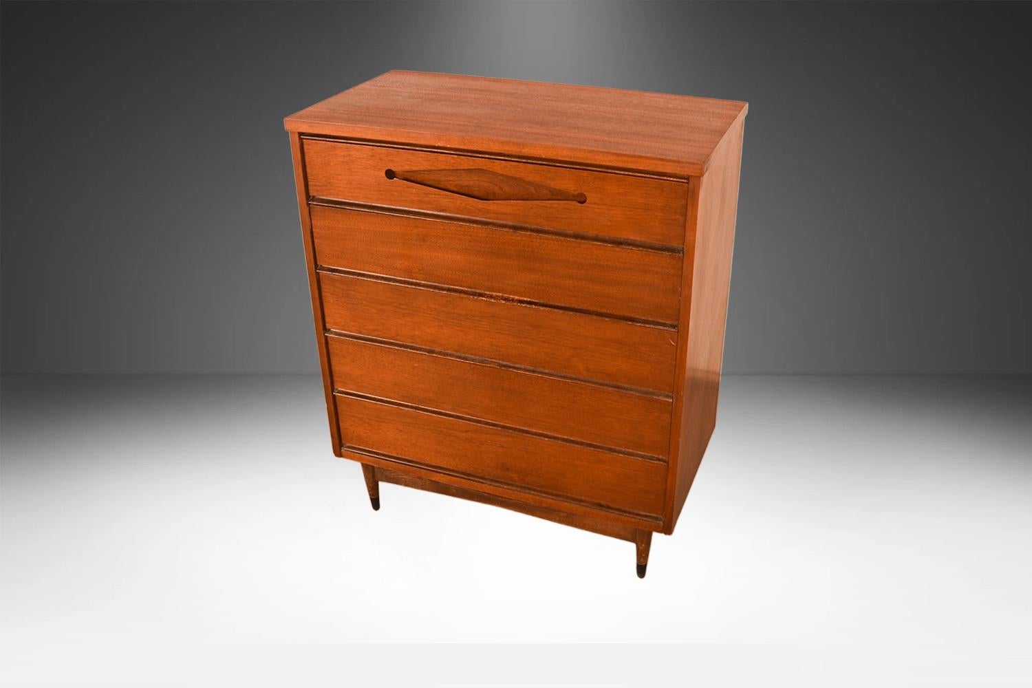 Bellissima cassettiera alta Bassett di met�à secolo moderno, circa 1960. La cassa e la struttura in legno di noce, splendidamente rifinita, ospitano cinque cassetti. Il cassetto superiore è dotato di un attraente tiretto scultoreo. Timbro del