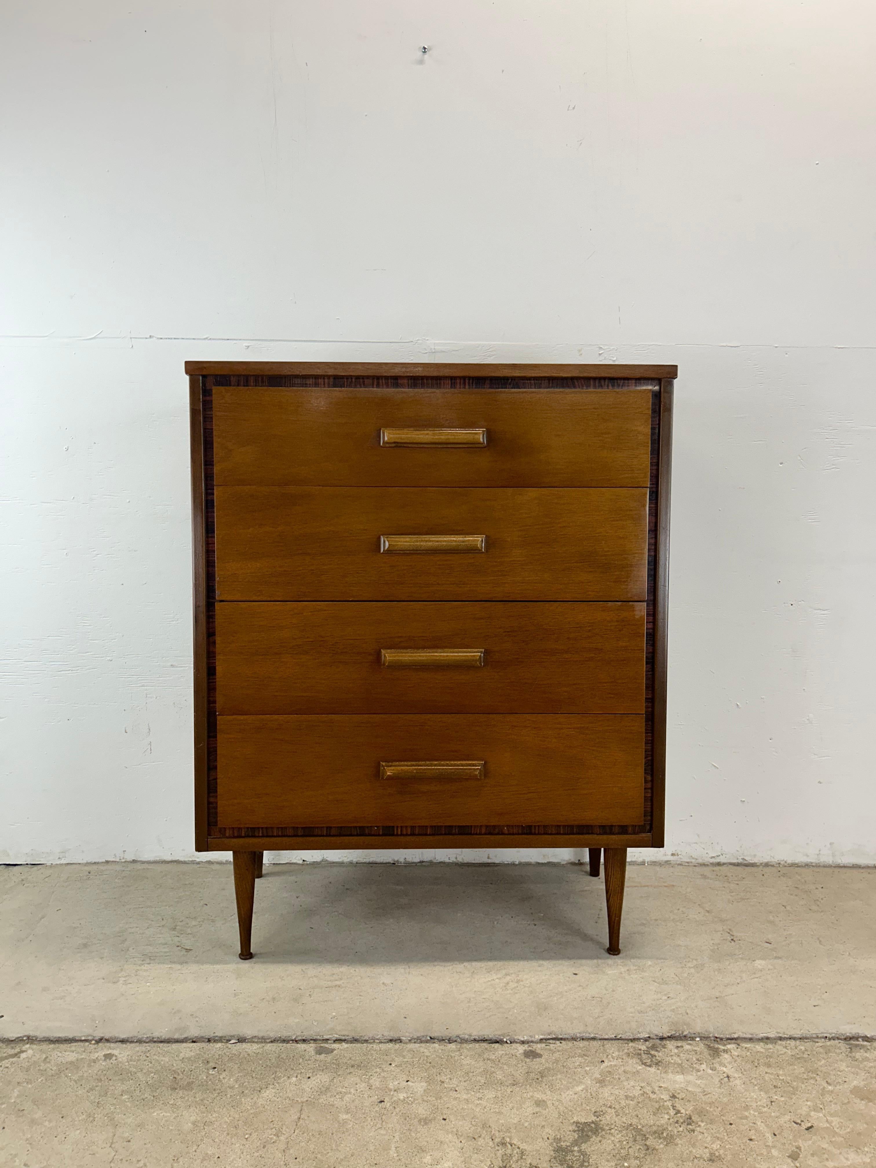 This mid century modern highboy dresser by Bassett Furniture features hardwood construction, walnut veneer with original finish, unique rosewood inlaid trim, four dovetail drawers with sculpted wood pulls, durable formica top with faux wood grain,