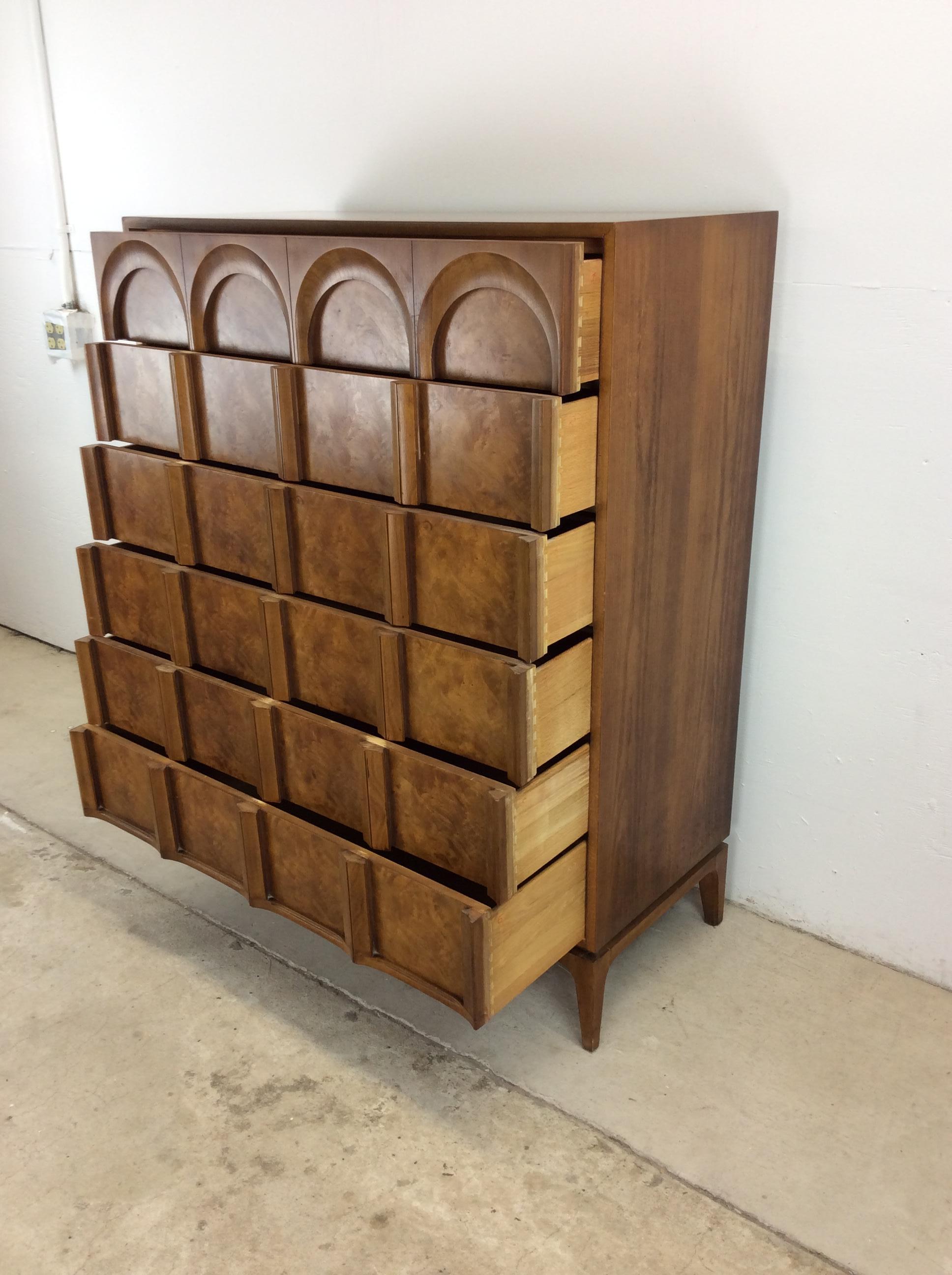 This mid century modern highboy dresser by Thomasville features hardwood construction, beautiful burlwood veneer with original finish, six dovetailed drawers with unique arched fronts, and tall tapered legs.   Matching lowboy dresser and pair of