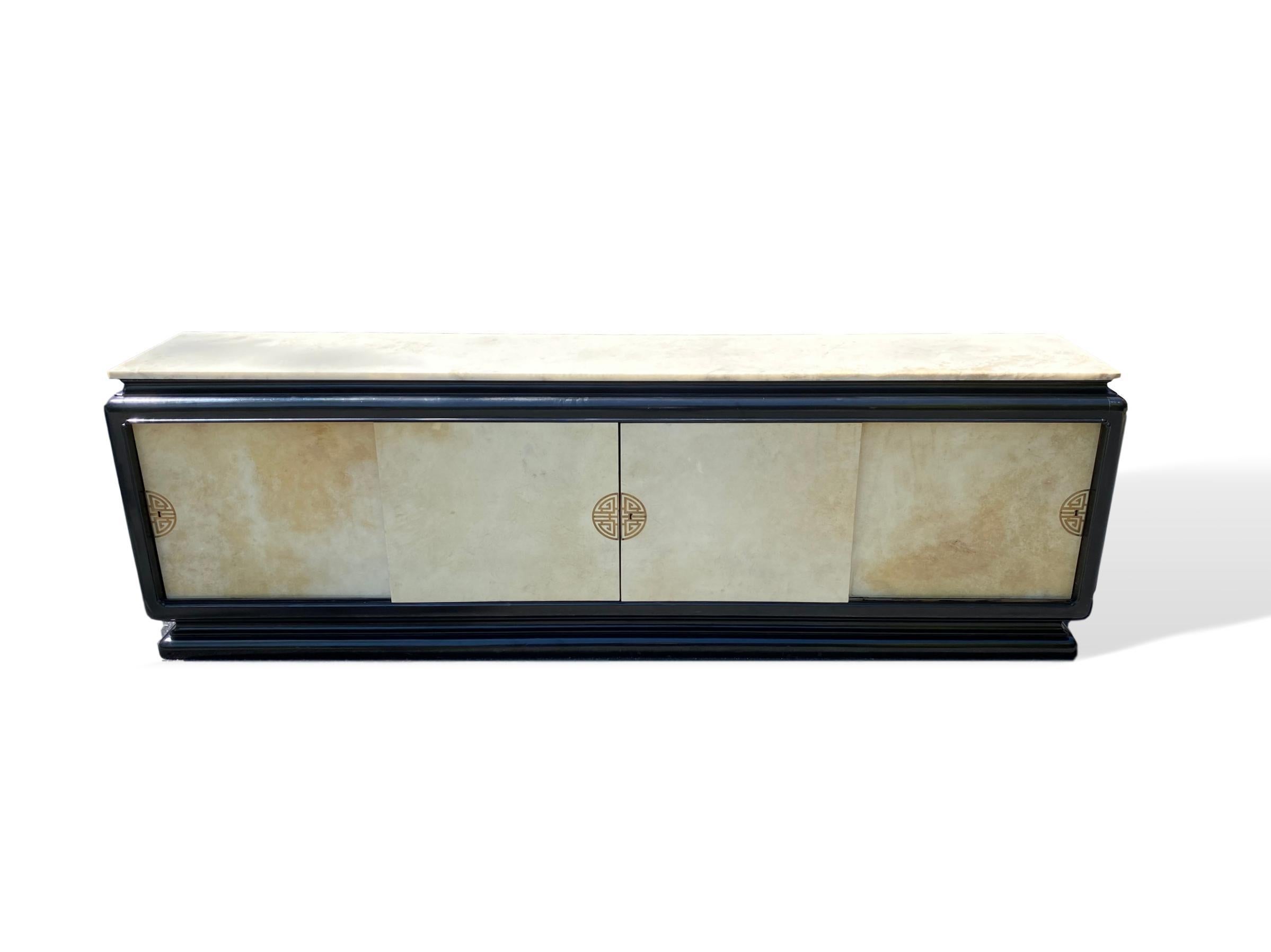 Mid-Century Modern Hollywood, Regency Art, Deco black lacquered credenza/sideboard with a Carrara Marble top, the black lacquered case with a shaped plateau top, raised panel moldings to the sides, with Parchment covered sliding doors, mounted with