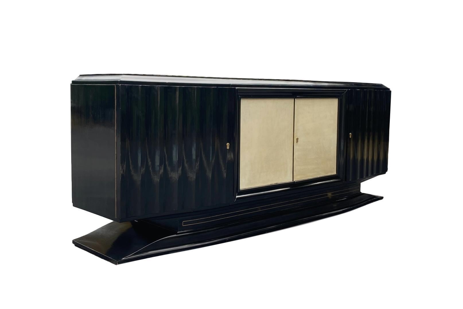 Mid-Century Modern Hollywood Regency Art Deco black lacquered and vellum sideboard, French, circa 1940, with inlaid bronze stringing, on a shaped floating base, the fitted interior lined in satinwood, with six drawers in figured walnut.