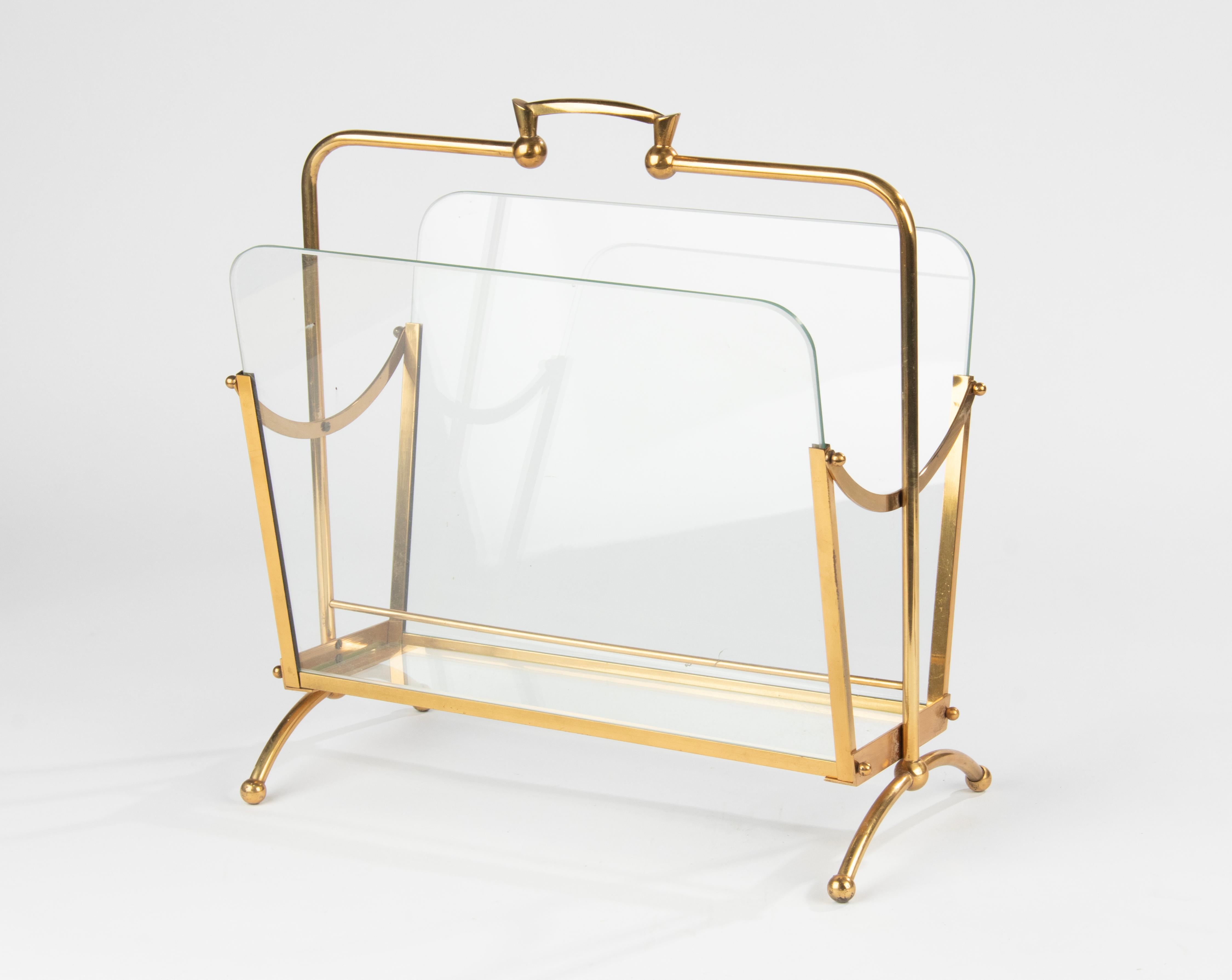 An Hollywood Regency style magazine rack/stand, made of brass colored metal. It has two compartments, divided by glass panels. The rack is in good condition, it is sturdy and stable, structurally correct. Made in Belgium around