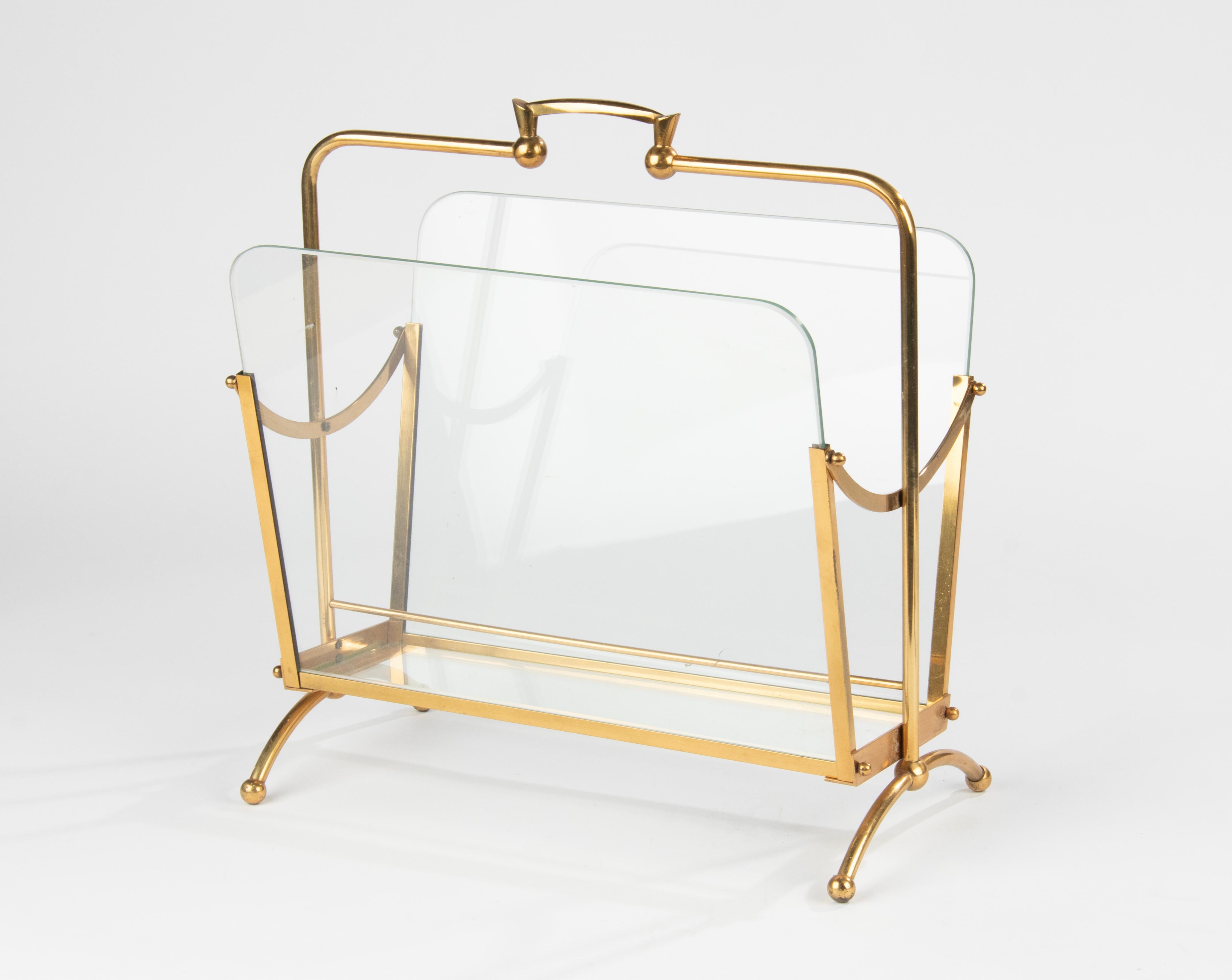 Porte-revues/support de style Hollywood Regency, en métal couleur laiton. Il comporte deux compartiments, divisés par des panneaux de verre. Le support est en bon état, il est robuste et stable, sa structure est correcte. Fabriqué en Belgique vers