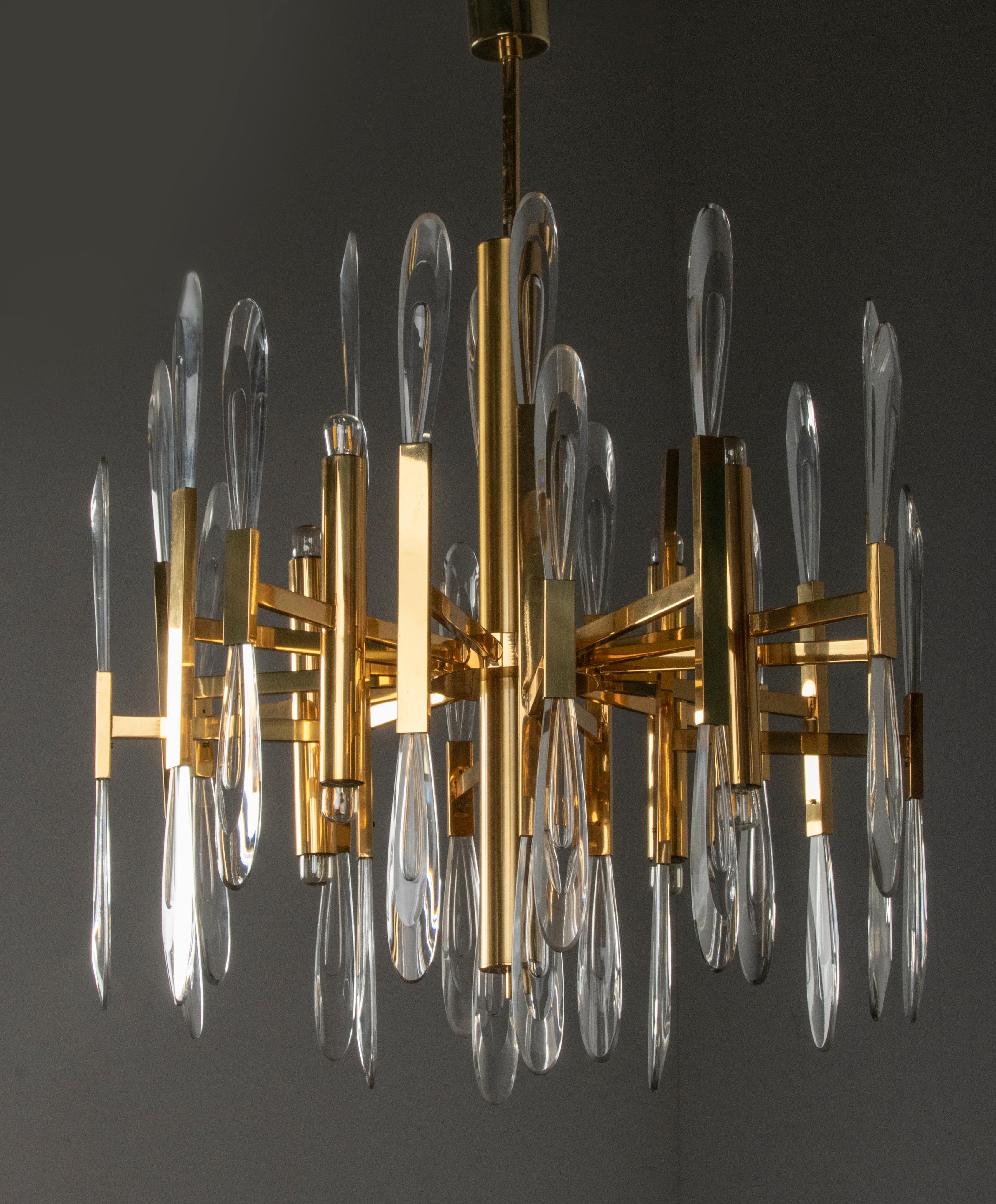 Italian mid-century chandelier by Gaetano Sciolari. It has eight lights, four lights pointing up, and four down. It is made from highly polished brass with crystal cut drops in the holders. It gives a beautiful atmospheric effect, the combination of