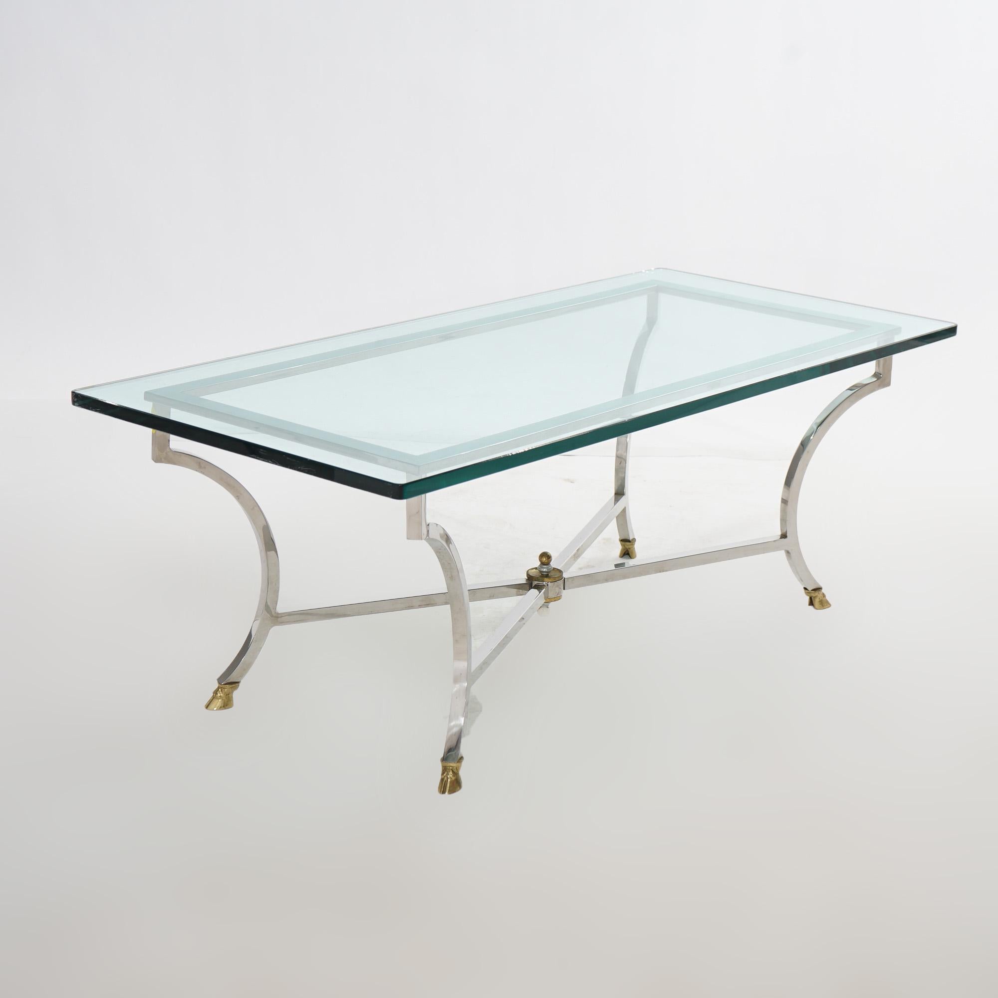A Mid Century Modern Hollywood Regency coffee table offers glass top over chrome base having stylized splayed legs terminating in brass hoof feet, c1960

Measures- 17.25''H x 48''W x 21.75''D