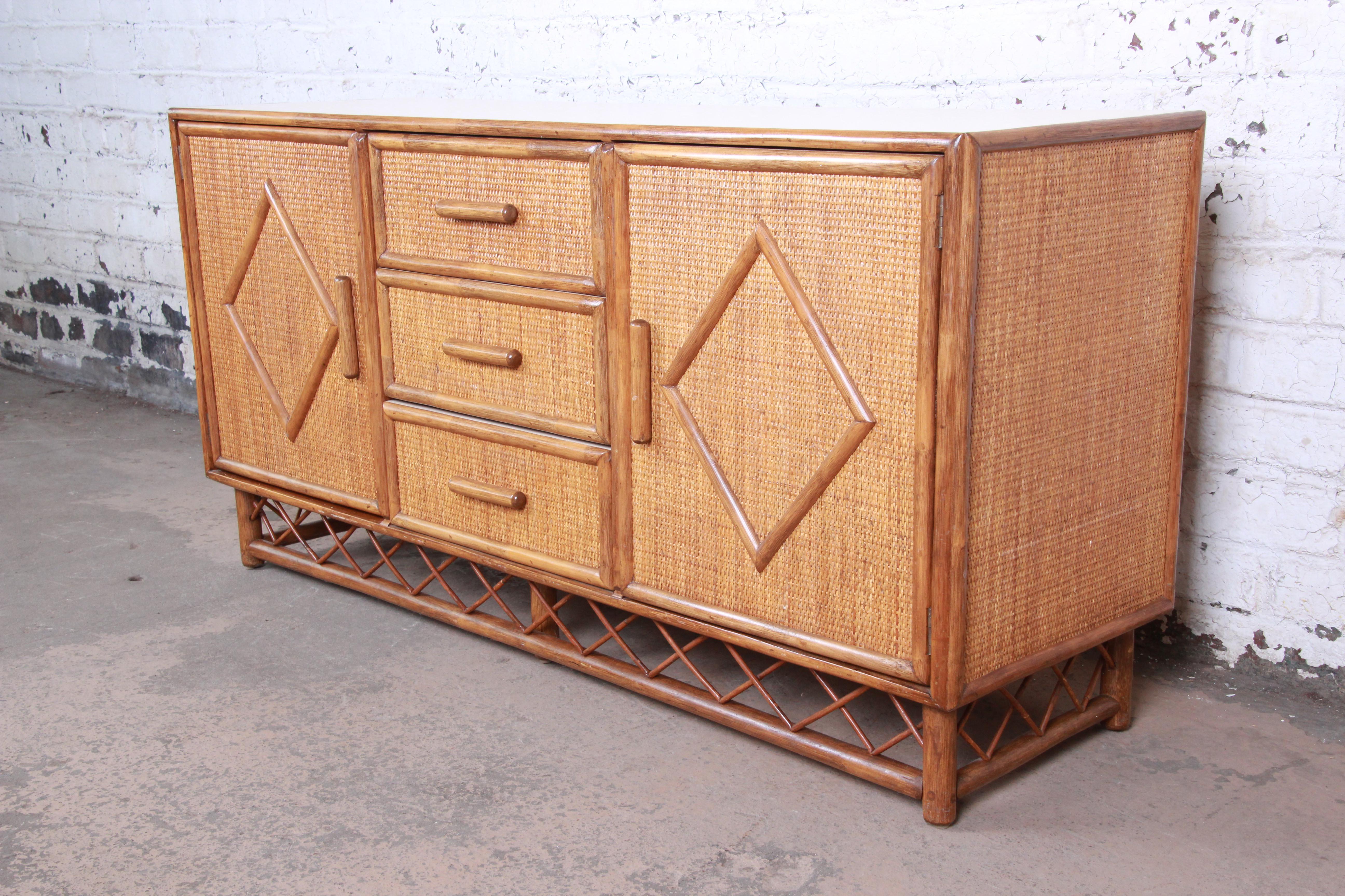 An exceptional Mid-Century Modern Hollywood Regency rattan and bamboo credenza or sideboard. The credenza features gorgeous woven rattan panels with bamboo frames. The case is raised on a decorative bamboo base. It offers ample storage, with shelved