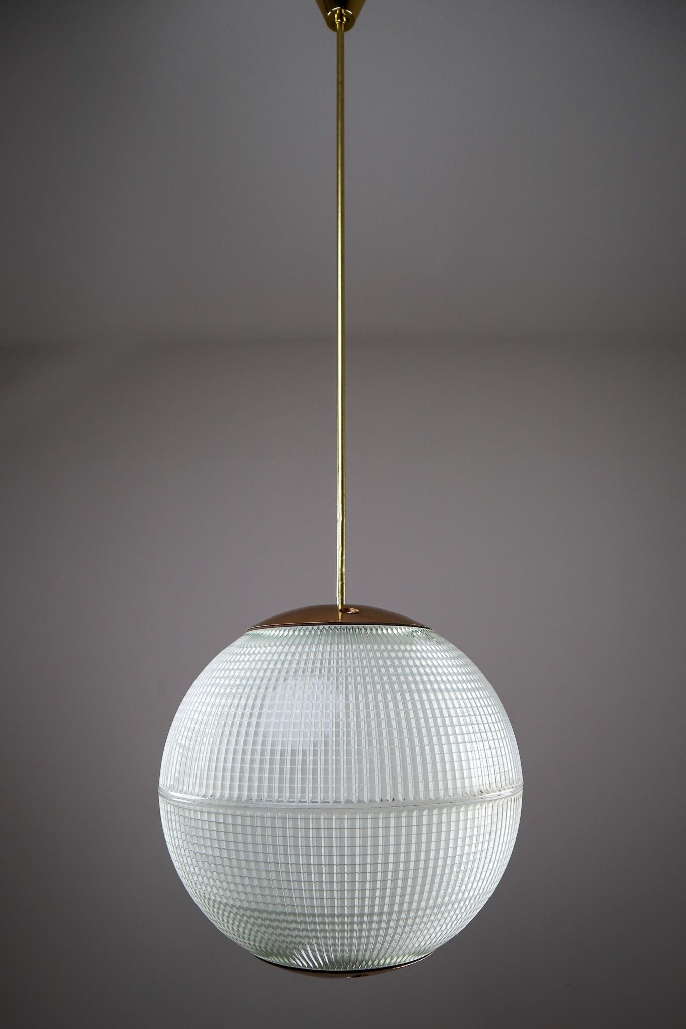 This is an 1960s Paris globe Holophane street light from Paris, France now turned into a pendant light with brass rod and brass colored details. The hallmark of Holophane luminaries, or lighting fixtures, is the borosilicate glass reflector /