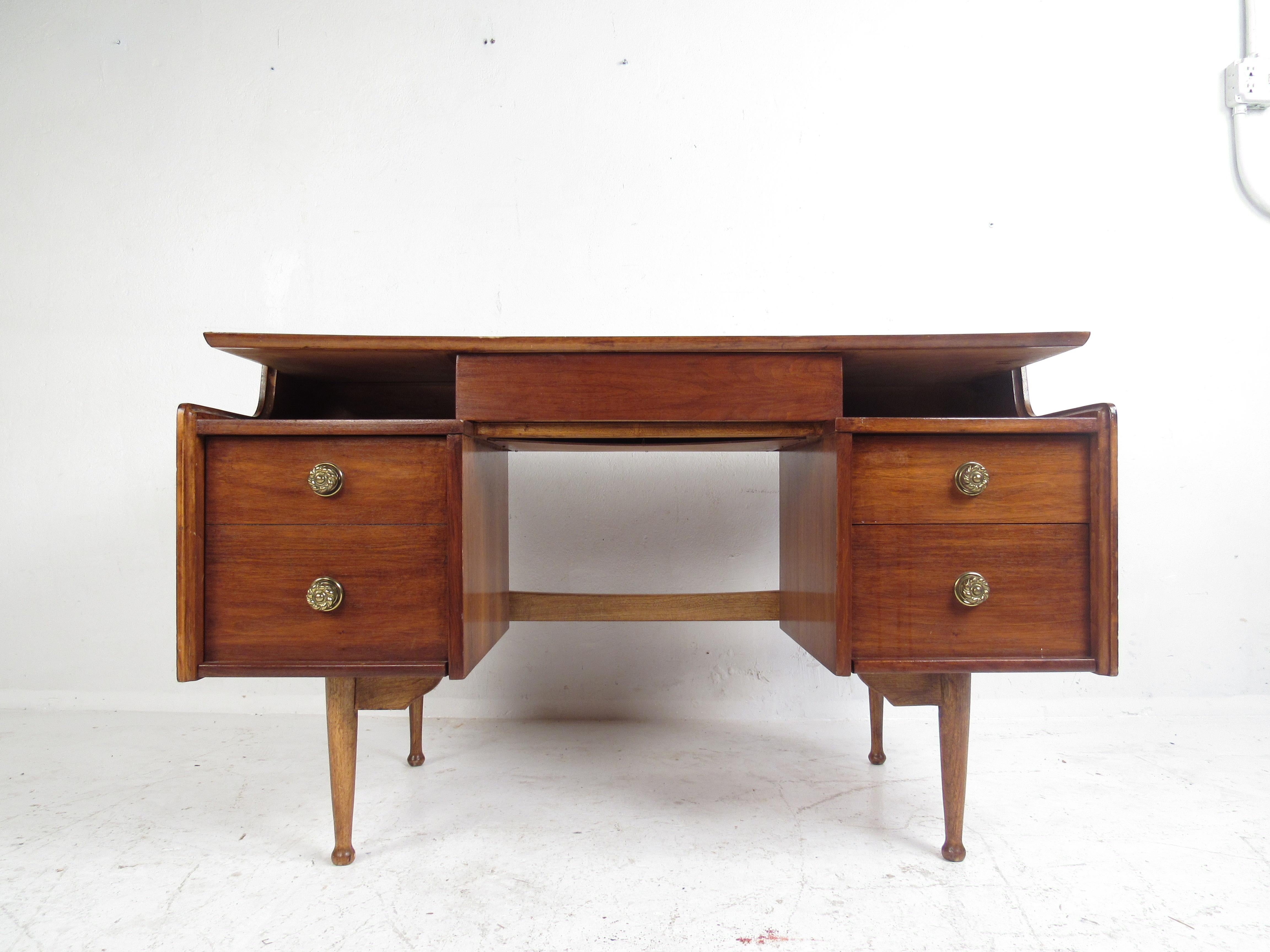 This gorgeous vintage modern desk boasts a floating top offering plenty of workspace. A well constructed piece with a finished back, drumstick legs, and a hidden center drawer. The sleek design has five hefty drawers ensuring ample room for storage.