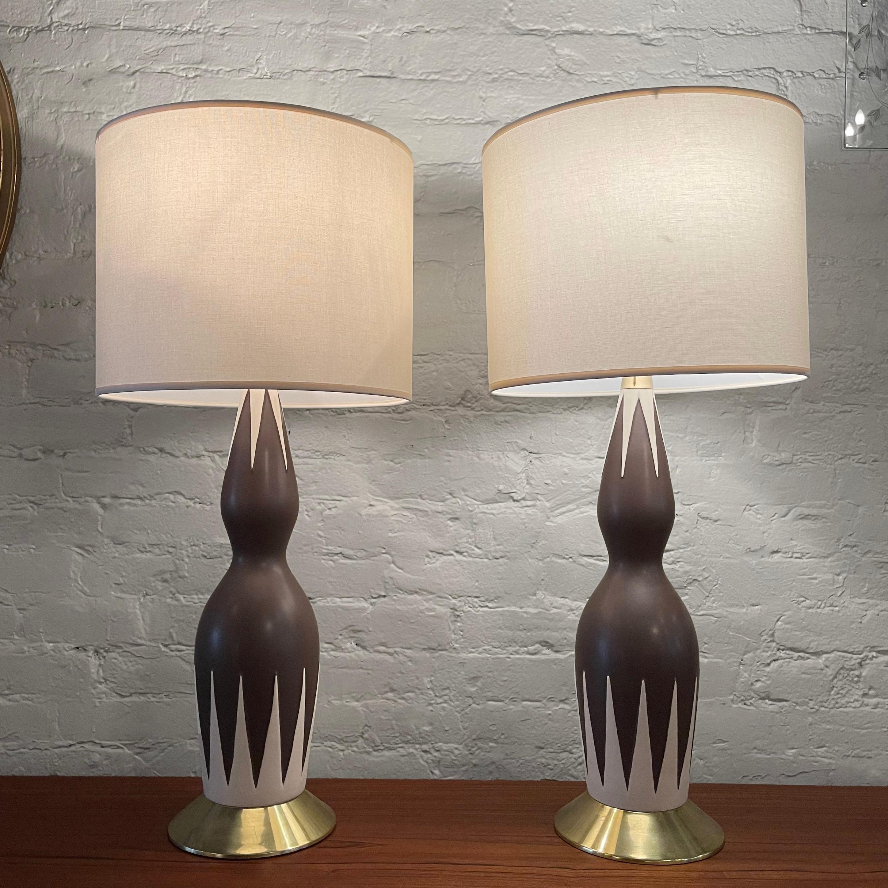Pair of striking, Mid-Century Modern, table lamps by Gerald Thurston for Lightolier feature brown and beige ceramic hourglass bodies with brass accents - base, neck, pull chains and original finials. The lamps accept 3 bulbs each up to 120 watts.