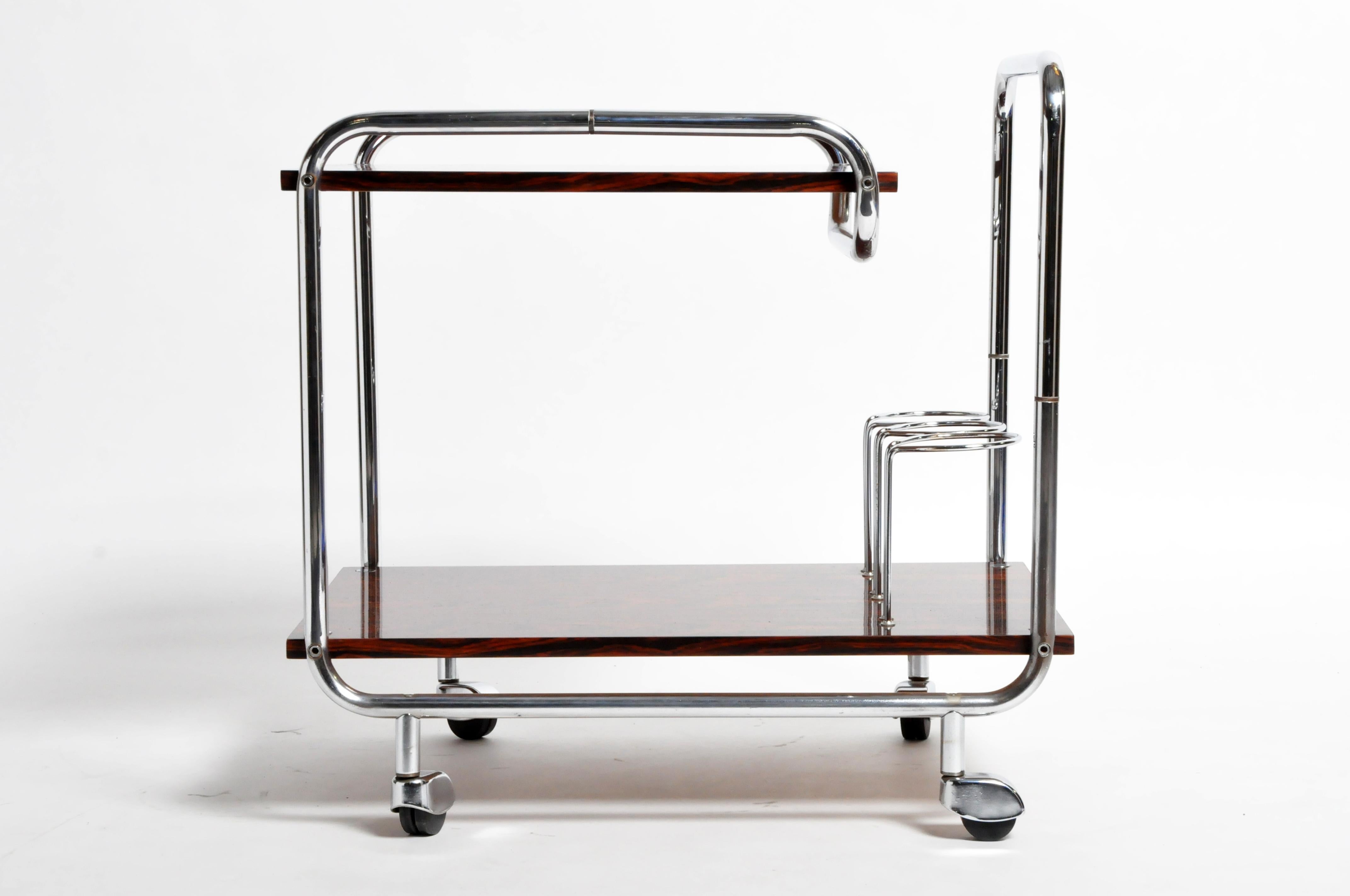 This elegant bar cart is from Hungary and was made from rosewood and chrome, circa 1960. The bar cart features 2 shelves, 3 bottle holders, wheels, and handle for easy transportation and movement. Wear consistent with age and use.