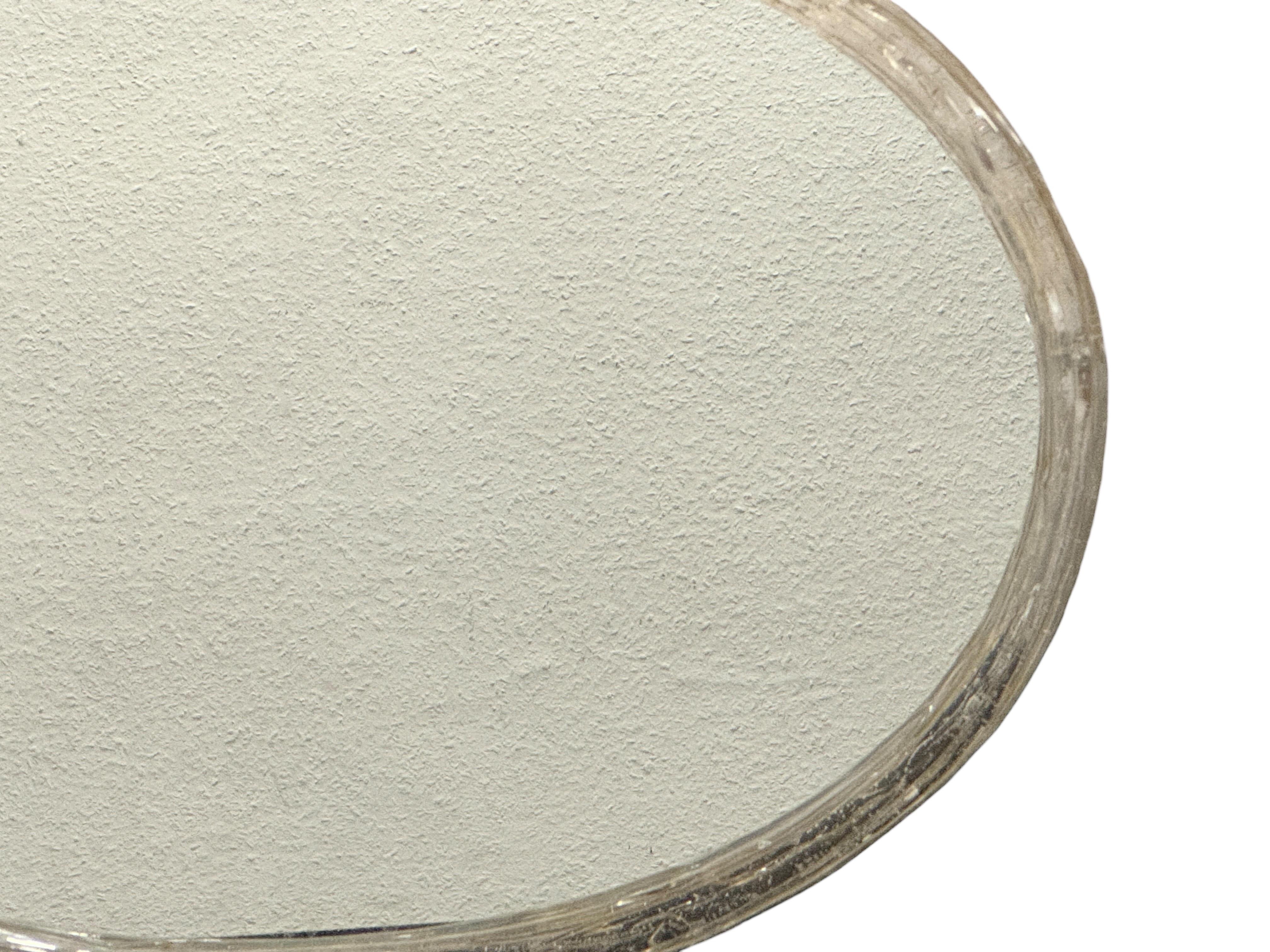 Un sorprendente specchio ovale in lucite e vetro risalente agli anni Sessanta. Questo elegante pezzo è caratterizzato da una cornice in lucite trasparente che mette in risalto il vetro smussato centrale, creando una presenza leggera, ariosa e
