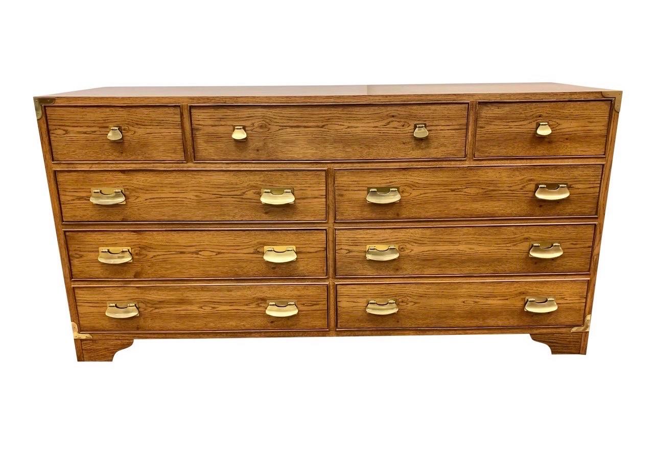 Iconic and elegant mid-century modern campaign style nine drawer dresser with brass hardware. Comprised on nine dovetailed drawers, three being on top and six on the bottom of equal size. Own the best!