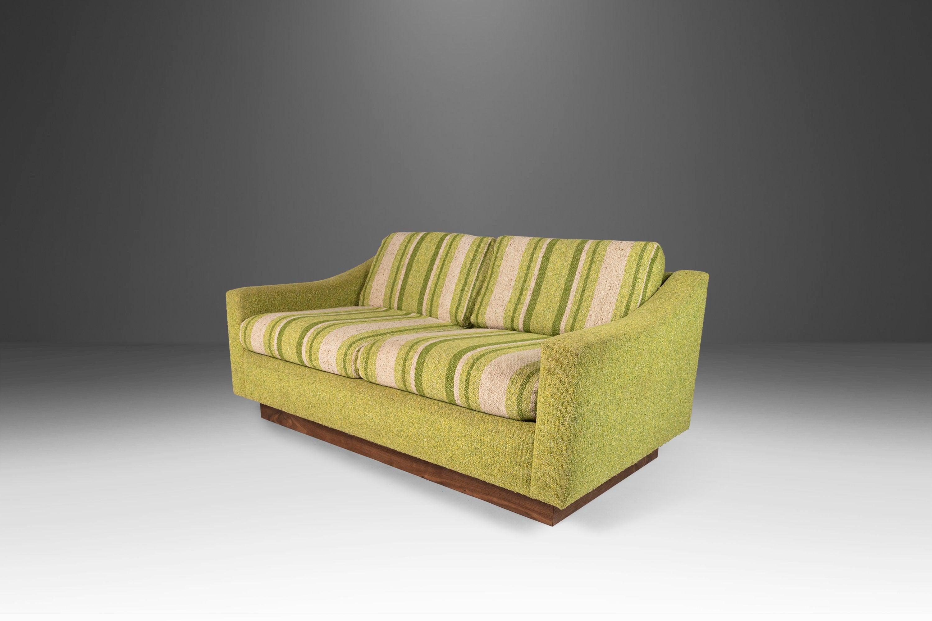 Equal parts comfort and retro style this eye-catching loveseat, attributed to Milo Baughman, is fresh out of the restoration shop and features a new plinth base made of solid black walnut. The original tweed upholstery, in a fabulous lime green with