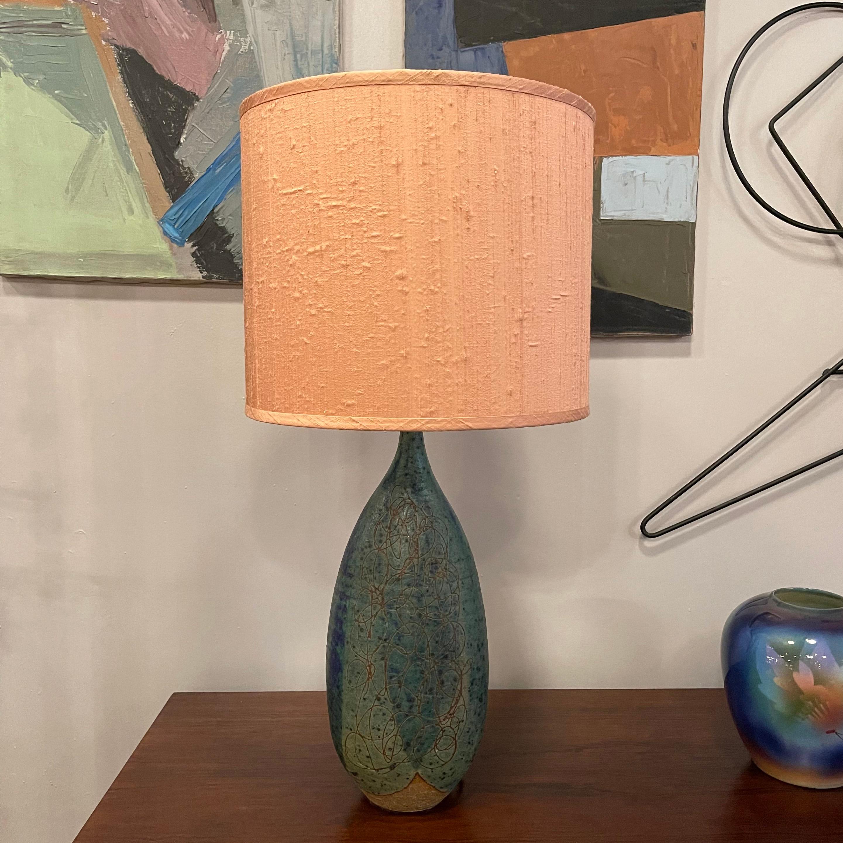 Stunning, Italian, Mid-Century Modern, art pottery table lamp features a 15 inch ht, gourd-shaped base in muted blue and green tones with incised pattern over top. The blush pink raw silk shade 12 inch diameter x 10 inch ht is included.

 