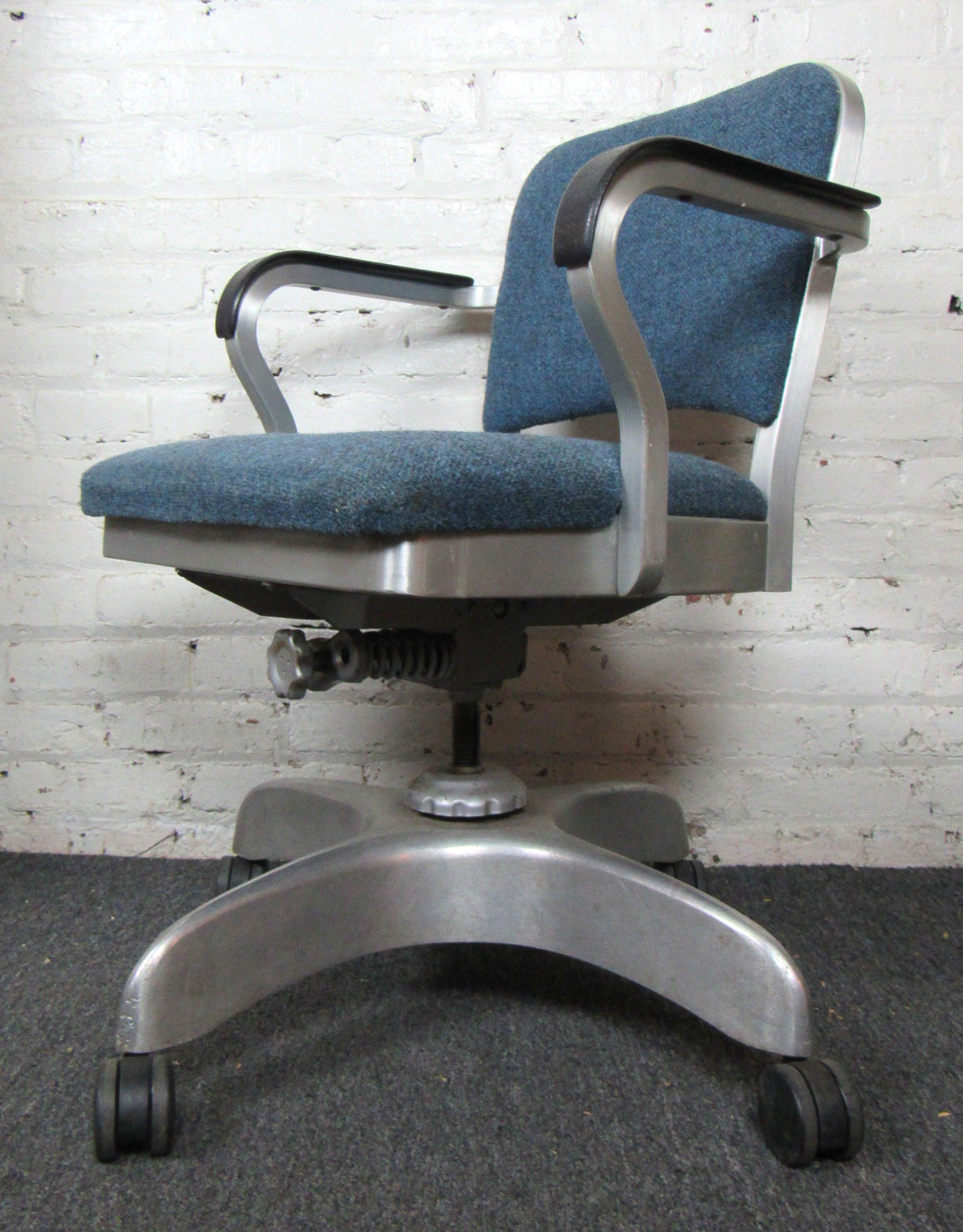 Vintage desk chair by prominent chair manufacturer Emeco. Soft cushions upholstered in blue fabric, rolling casters and adjustable seat. Emeco chairs are famous for their durability, comfort, and iconic design. Chair comes with original delivery tag