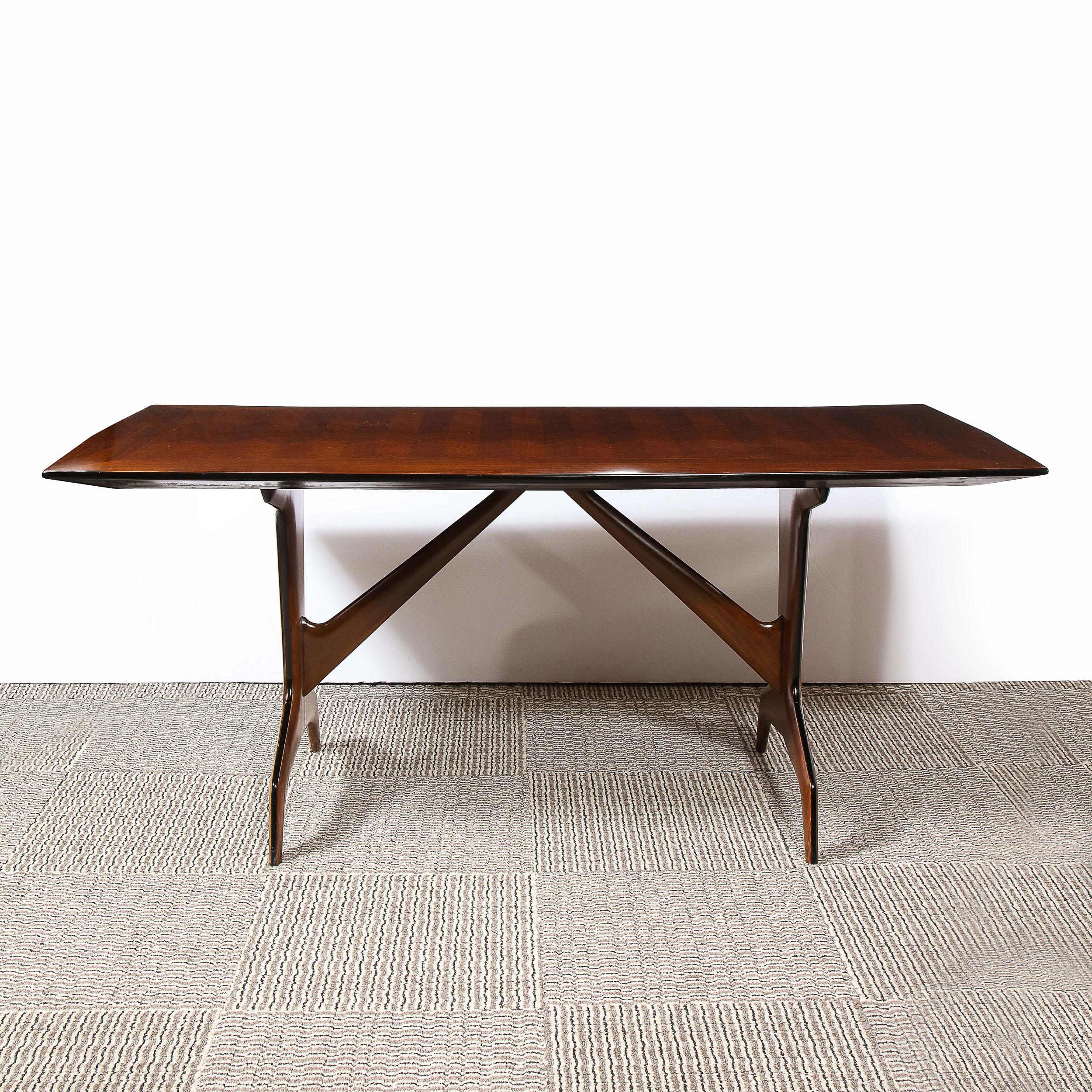 This stunning Mid Century Modern dining table was realized by the legendary designer Carlo De Carli in Italy, circa 1950. It features a graphic and sculptural base consisting of two tapered rectangular supports that adjoin geometric arched bases