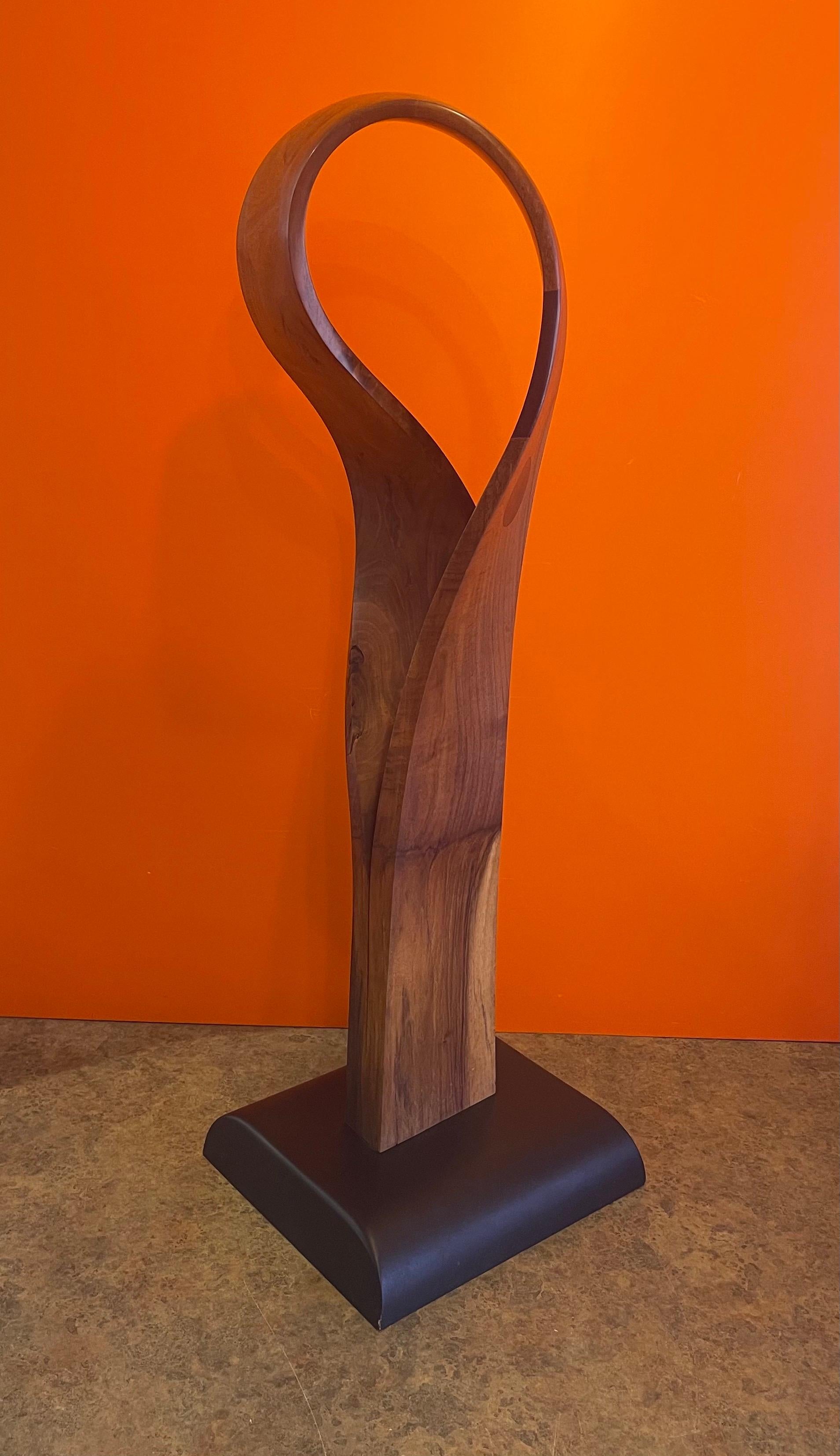 Magnifique sculpture abstraite de forme libre en bois incrusté, datant des années 1980. La pièce est assez spectaculaire avec des cercles incrustés sur un morceau de bois de ronce en forme de ruban sur une base noire de 11 