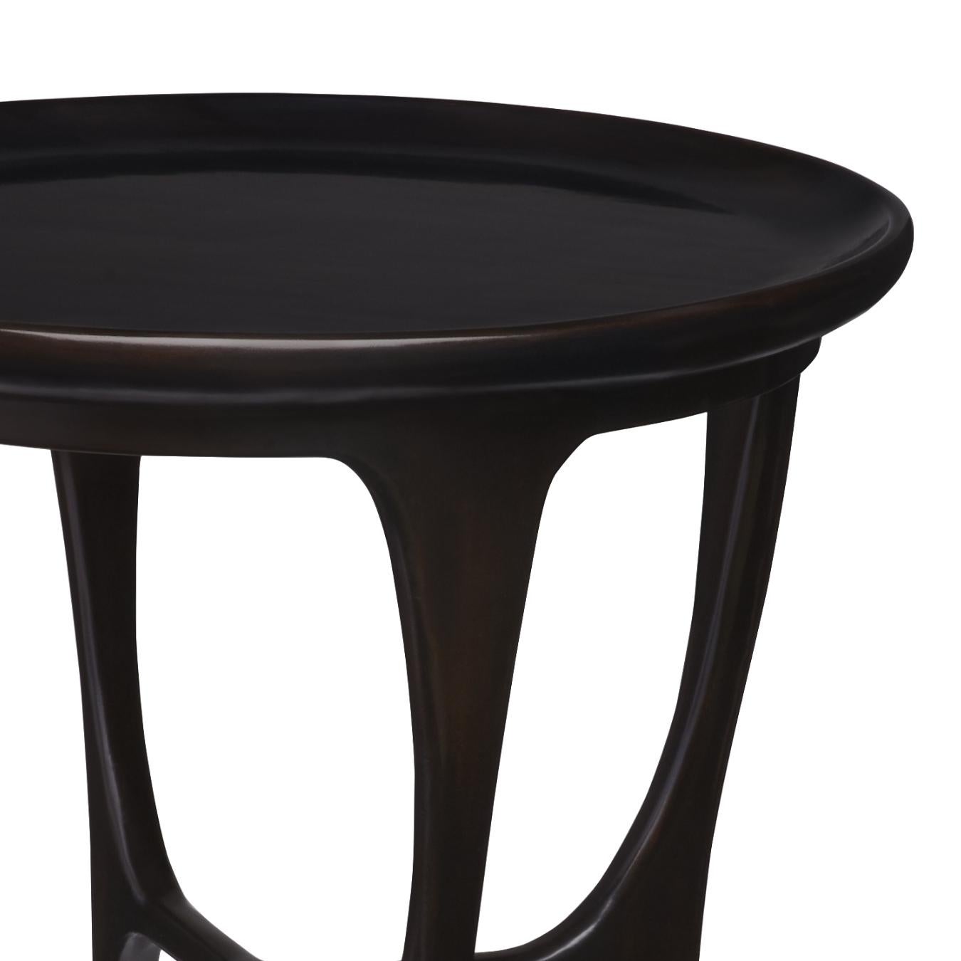 Cette table d'appoint s'inspire du style Mid-Century Modern et est conçue avec des pieds stylisés, un plateau concave et des pieds coiffés de laiton.
 