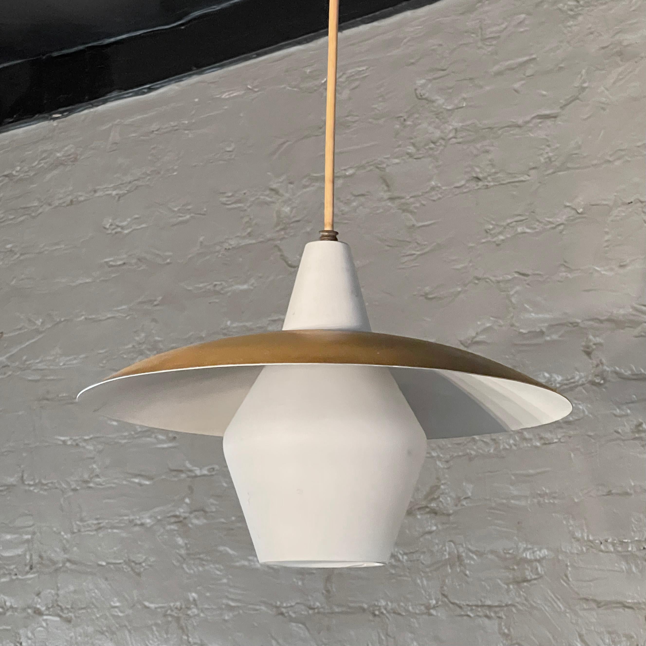 Mid century modern pendant light features a frosted glass lantern shade with an intersecting metal disc with gold exterior and white interior in the style of Gerald Thurston, Lightolier. The pendant hangs at an overall height of 36 inches.