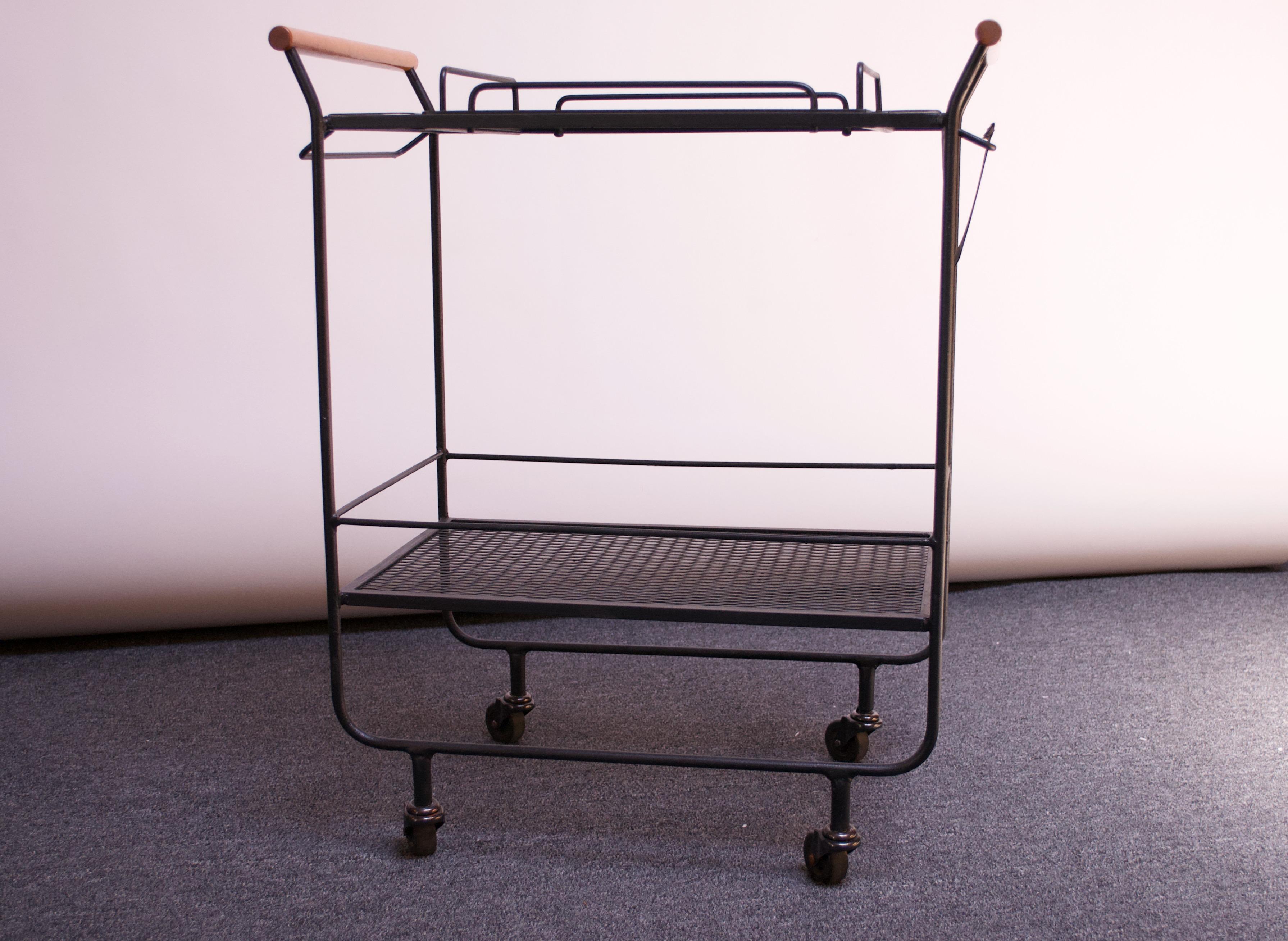 Minimal, modernist bar cart / tea trolley featuring two perforated iron surfaces with four larger glass holders on one side, and six on the other (given the age of production, these holders were likely intended for tapered high balls and champagne