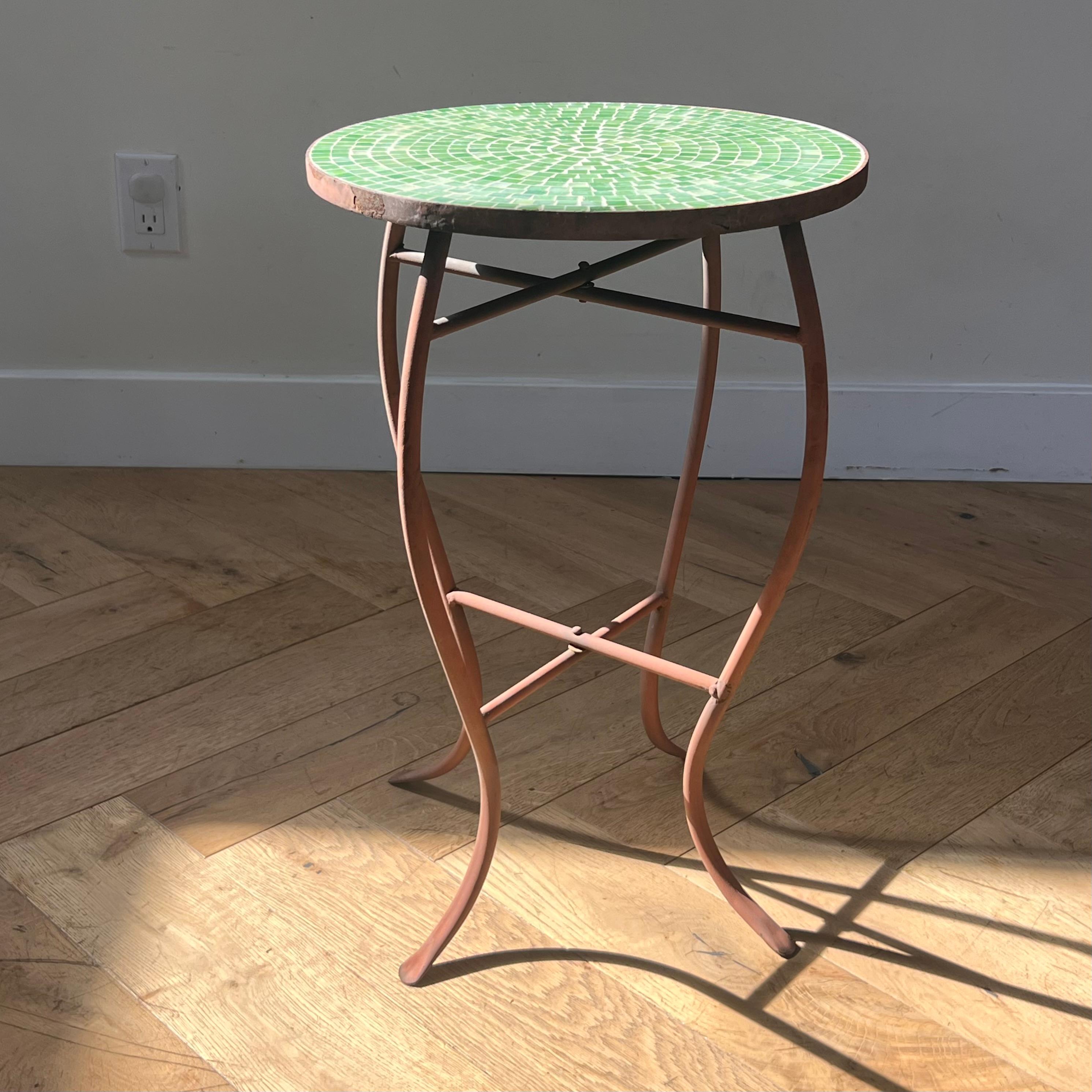A mid century iron and green mosaic tile side table, early 1960s. Tones of green range from grass green to vermillion and chartreuse. Some insignificant wear; see pics. Pick up in central west Los Angeles or we ship worldwide. 
14” diameter X 21”