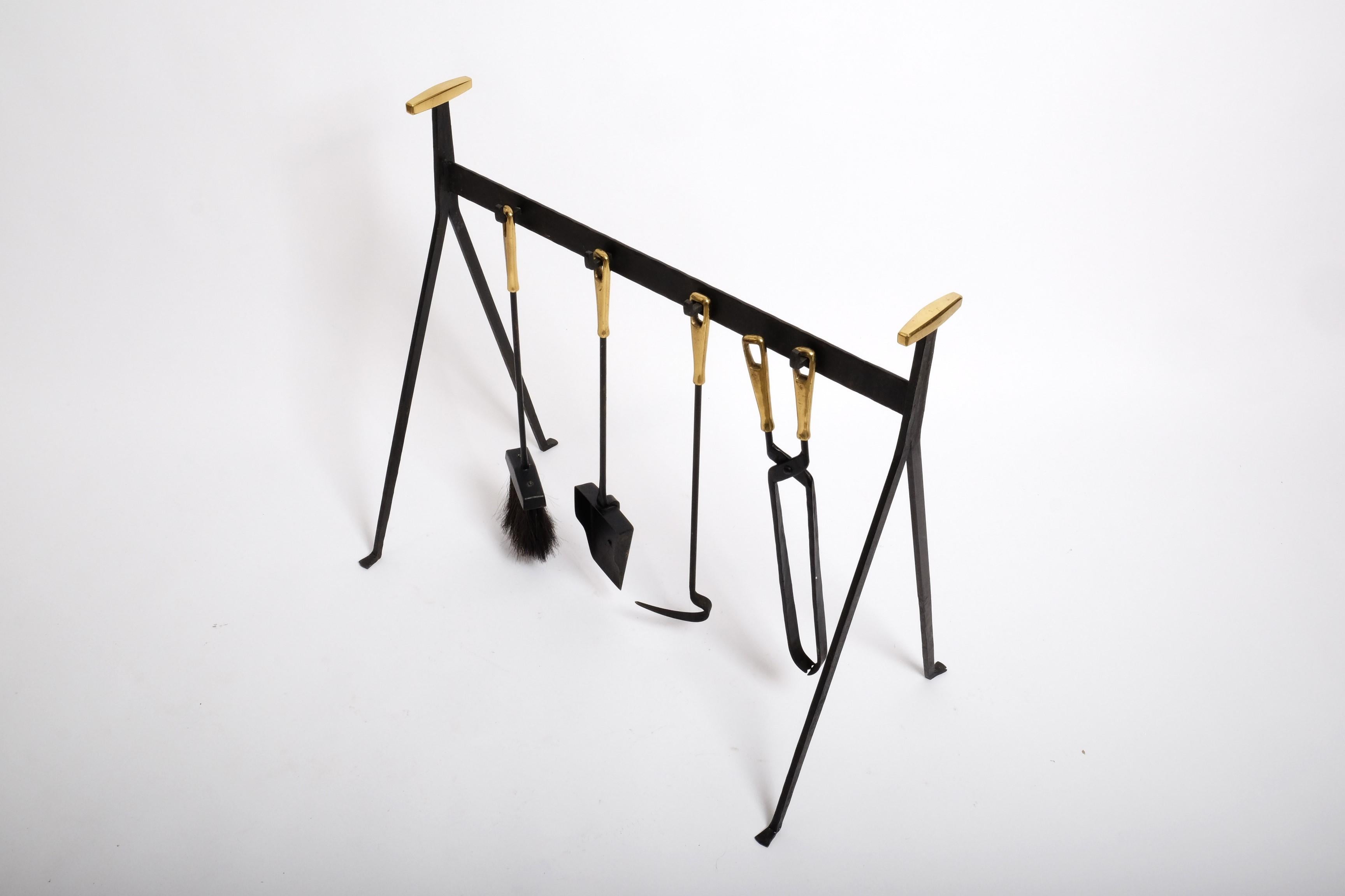 Great mid-century modern fireplace tool set by Vereinigte Werkstätten, made in Germany, 1960s. 

The fireplace tool set consists of a shovel, brush, hook, tongs and a stand. The fireplace tools and stand are made of blackened iron with brass