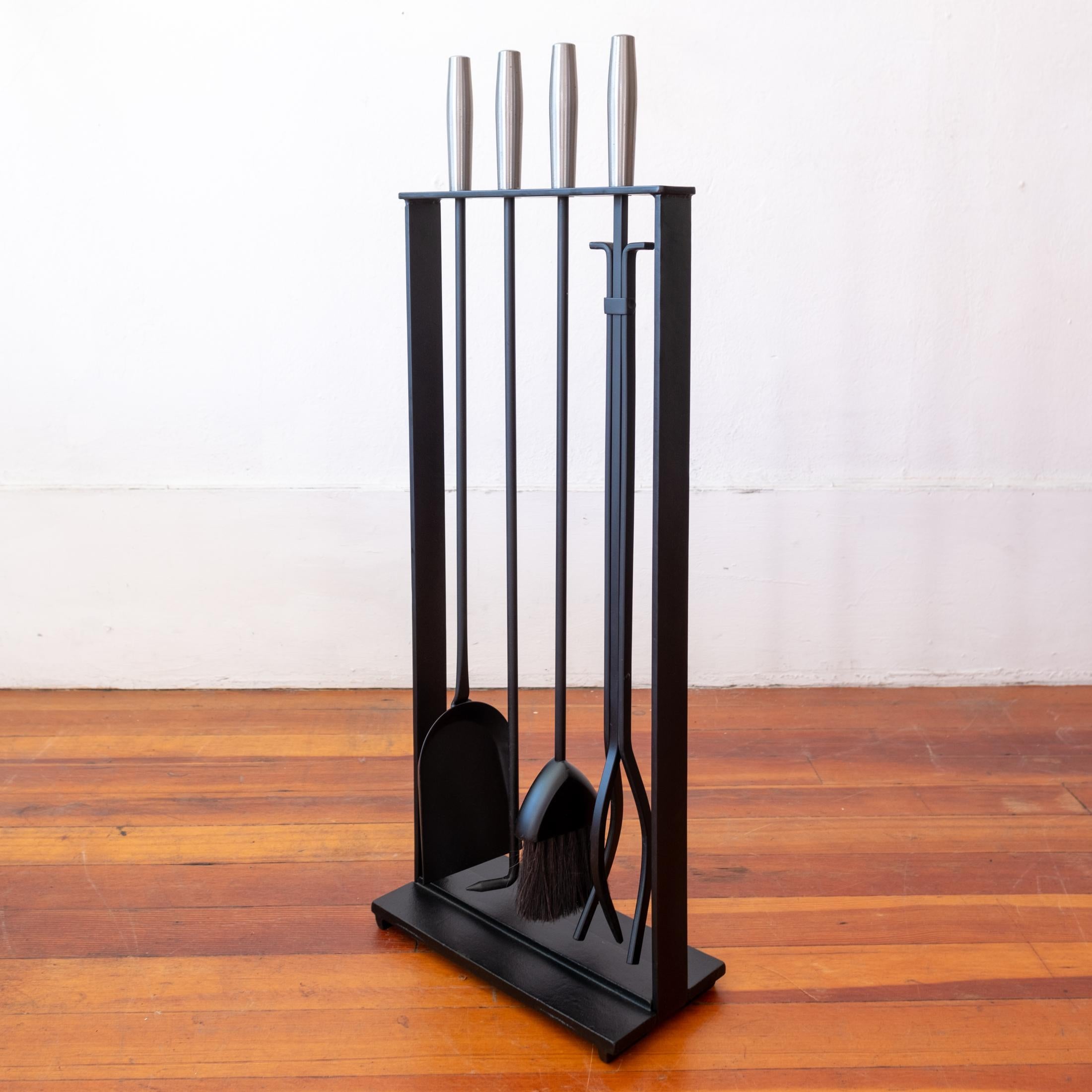 Un fantastico set di attrezzi da fuoco modernisti in ferro. Include un attizzatoio, una pinza per tronchi, una spazzola e una pala. Costruzione solida di alta qualità con un design minimalista. Marcato sul fondo del supporto in ghisa solida. 