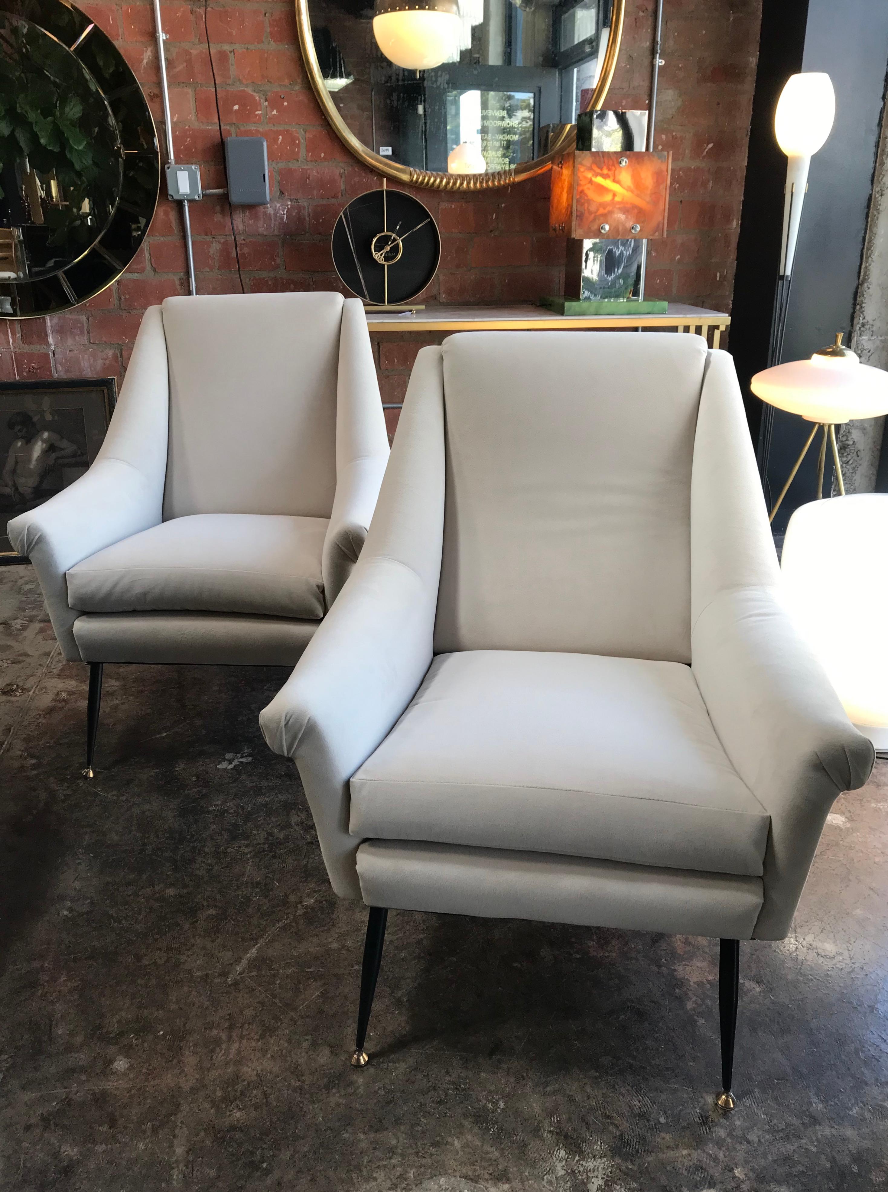 A pair of very stylish and extremely comfortable Italian midcentury armchairs or by Anonima Castelli, original from the 1960s with polished brass details on the legs. The seats are upholstered.