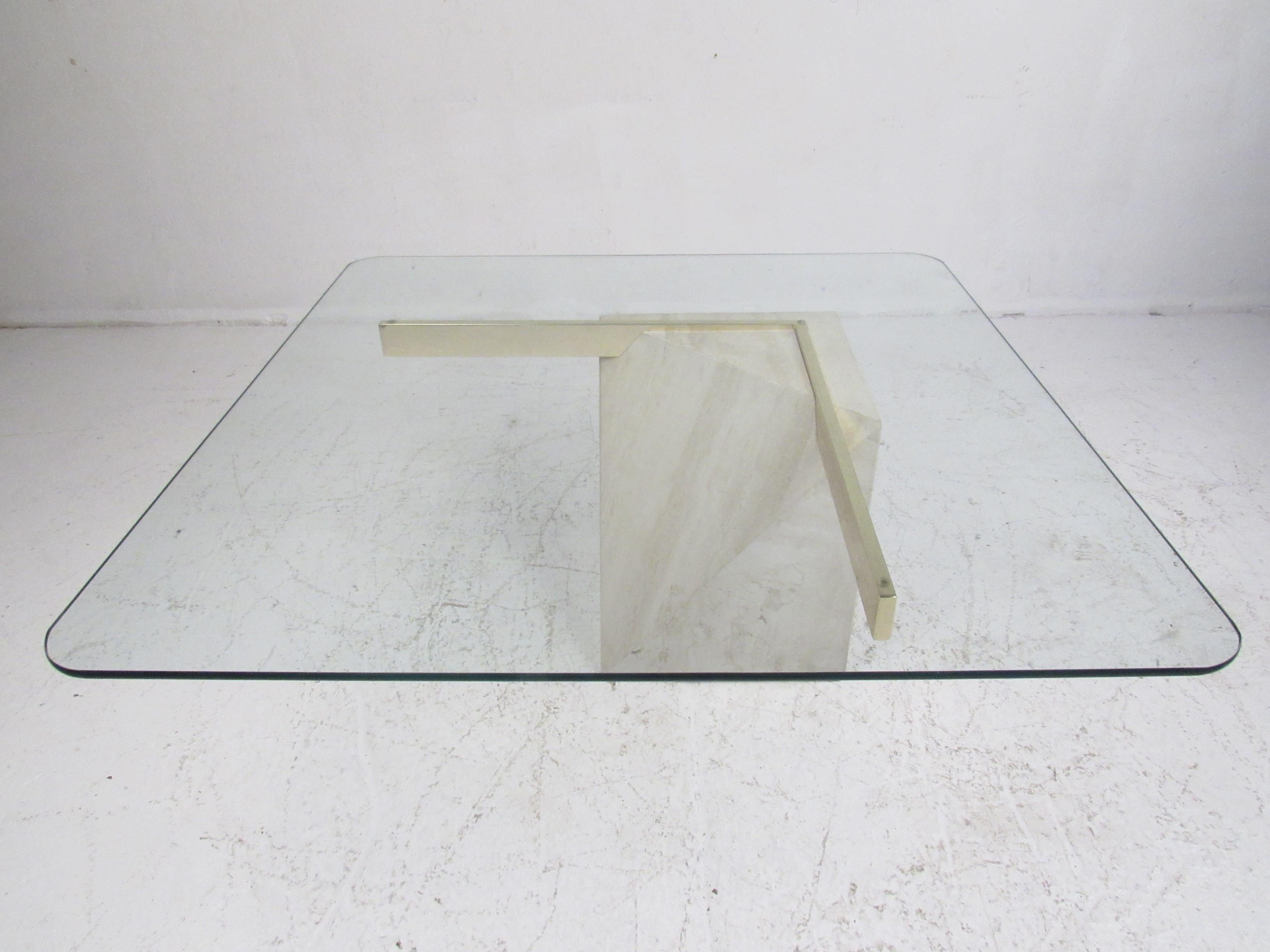This wonderful vintage modern cocktail table features a unique travertine base with brass plated bars supporting a thick glass top. The geometric shaped base allows the glass top to appear as if it's floating on one side. An elegant Italian design