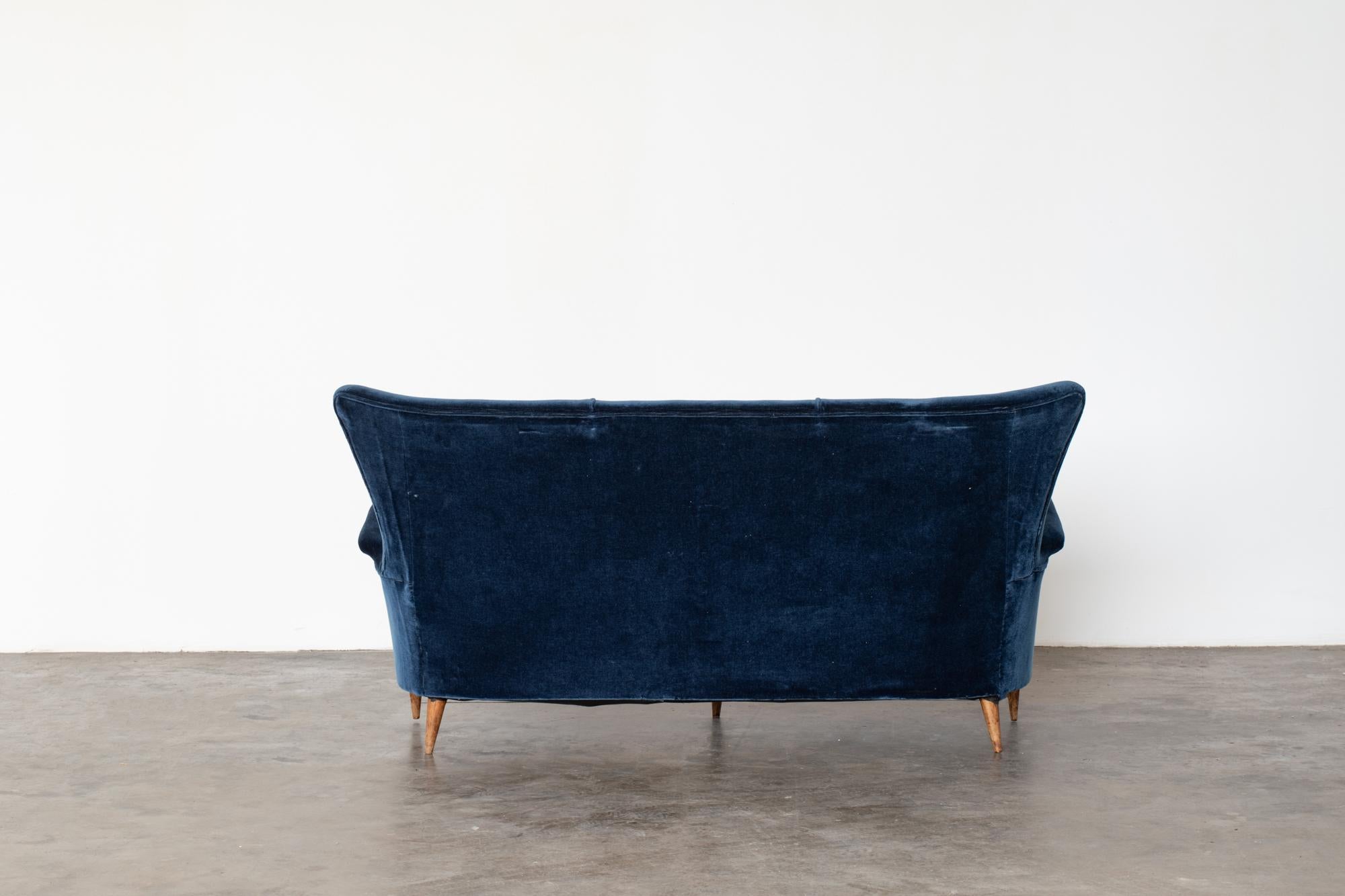 Elegant and timeless two-seat sofa. Italian design, structure and legs in solid wood, recent blue velvet upholstery, 1950s production.
 