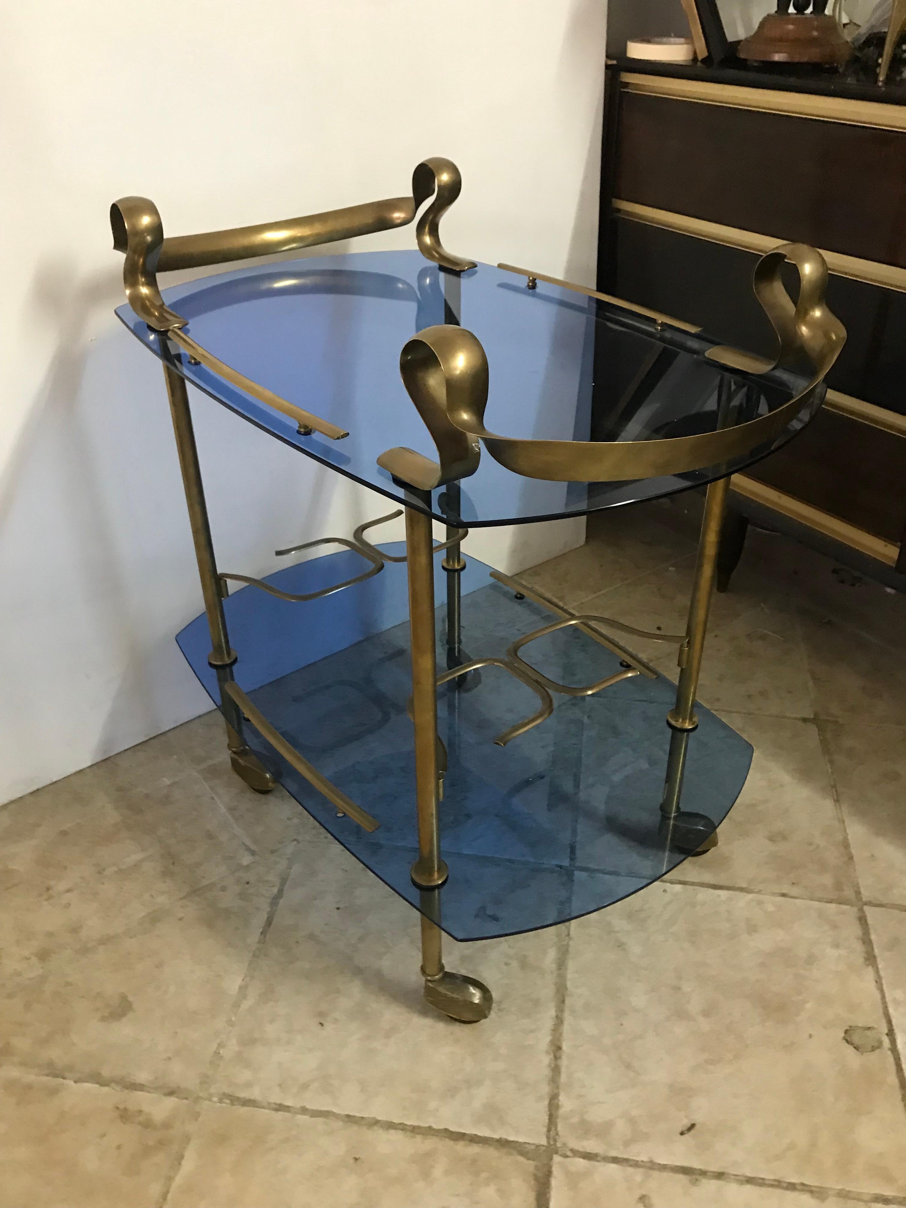 Beautiful and unique bar cart in brass and blue glass, Made in Italy, circa 1950.
This cart is very much in the style of Fontana Arte and Max Ingrand, but as of this moment we can only attribute it.