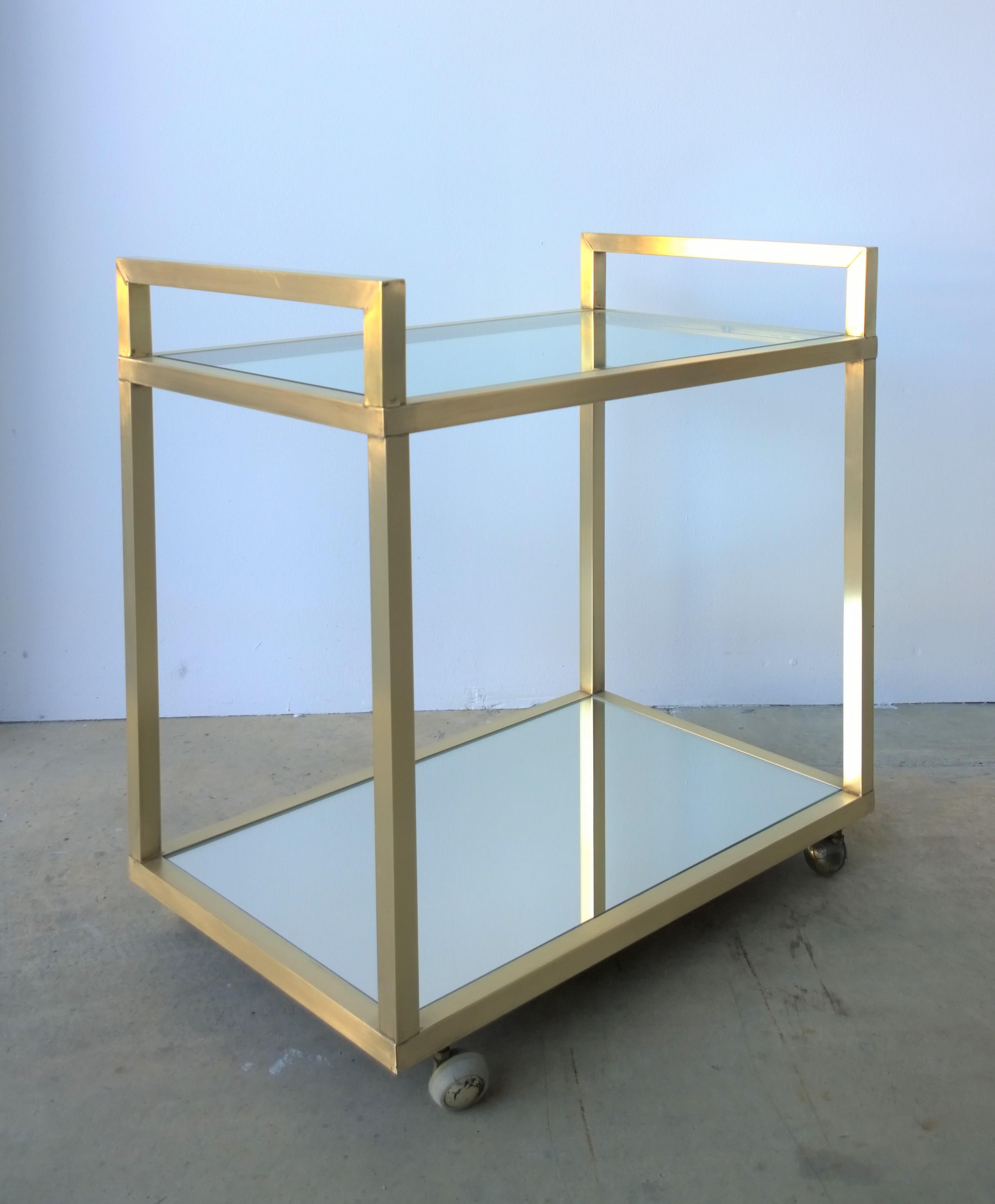 Offered is a Mid-Century Modern Italian brass with glass and mirrored glass two-tier bar cart with original brass and new upgrade casters. The mirror shelf on the bar cart has been replaced. The brass has been newly polished to a bright golden