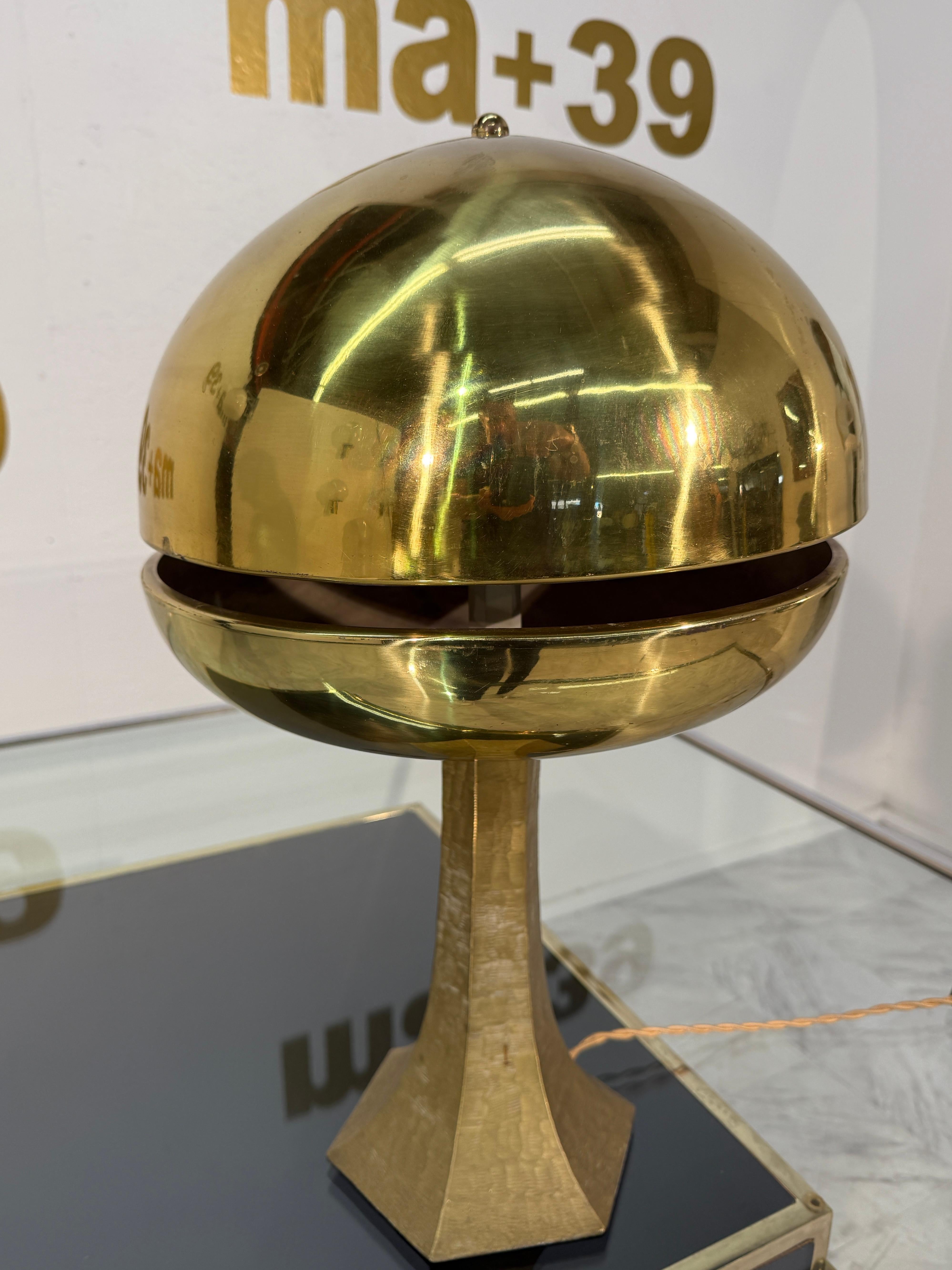 An exceptional mid-century modern brass table lamp with a bold sculptural presence. Featuring a split mushroom dome shade elevated on a hand-hammered brass pedestal, this piece captures the futuristic elegance of 1960s–1970s Space Age design.

The